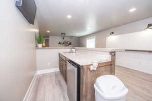 Wet bar featuring a granite-style countertop, undermount sink, built-in mini-refrigerator, and wood-finish cabinetry