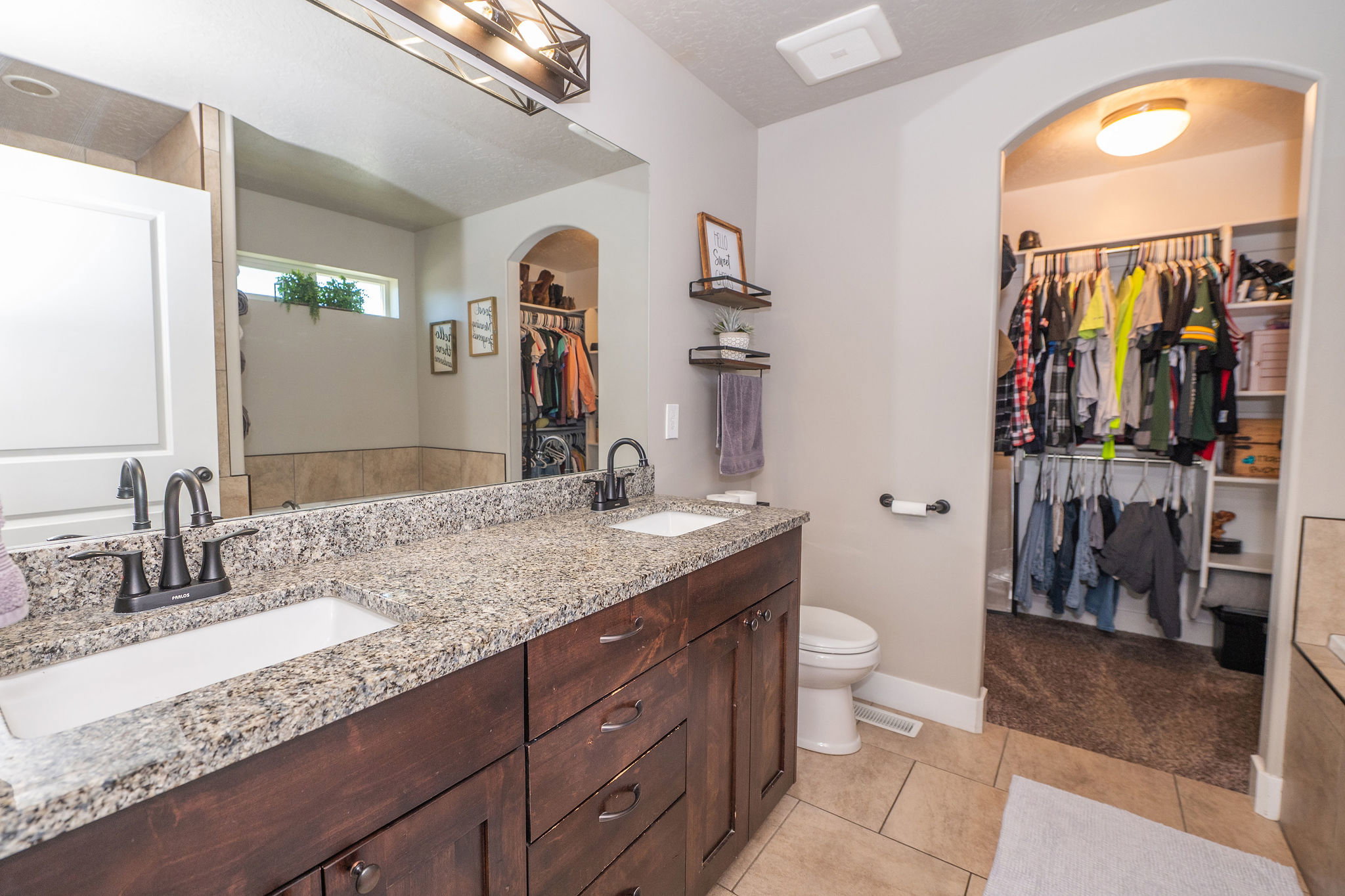 Double vanity with granite-style countertop, undermount sinks, and dark wood cabinetry