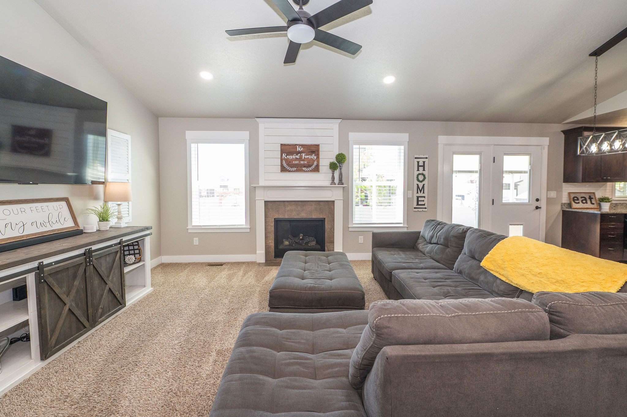Living area with a fireplace featuring a shiplap accent wall, recessed lighting, and a ceiling fan