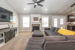 Living area with a fireplace featuring a shiplap accent wall, recessed lighting, and a ceiling fan