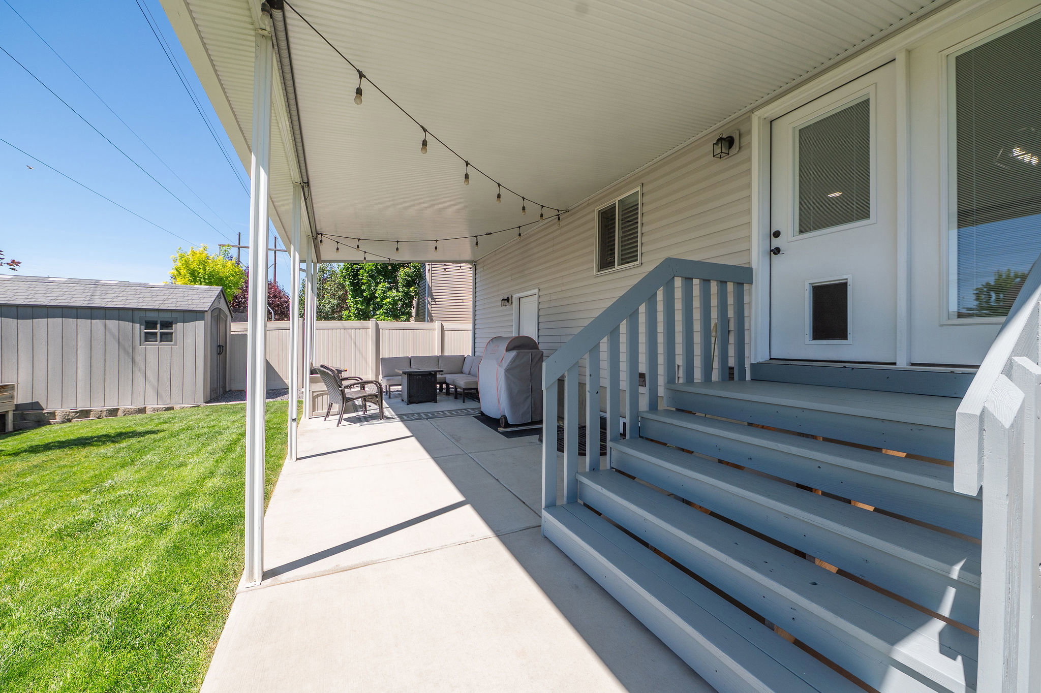 Covered patio featuring string lighting, concrete flooring, and direct access to a manicured lawn