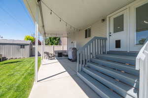 Covered patio featuring string lighting, concrete flooring, and direct access to a manicured lawn