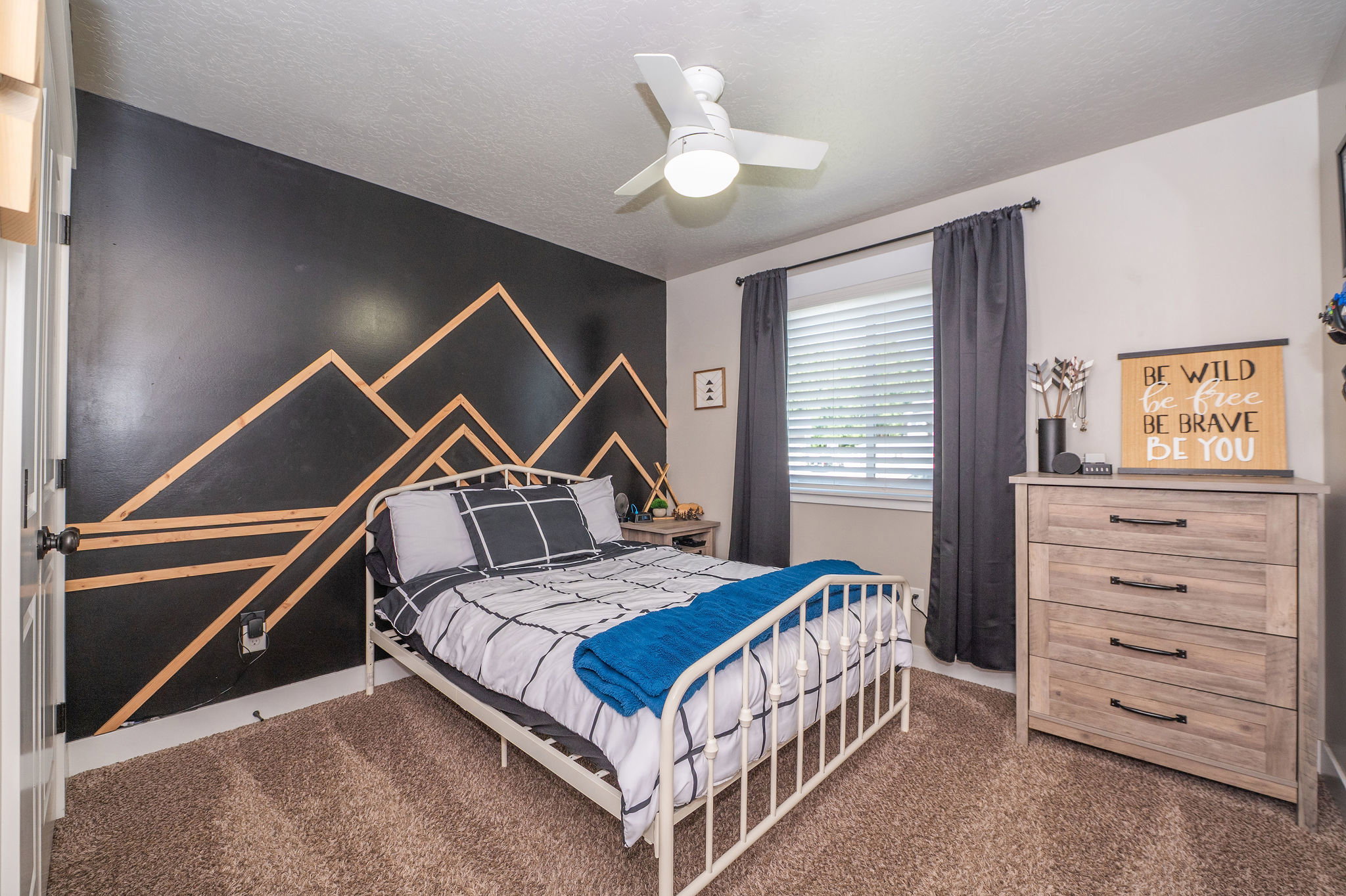 Bedroom featuring a decorative accent wall, ceiling fan, window with blinds, and carpeted flooring