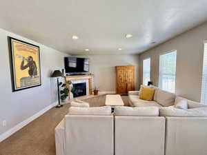 Living space featuring a fireplace with a light wood mantel and tile surround, recessed lighting, and multiple windows with blinds