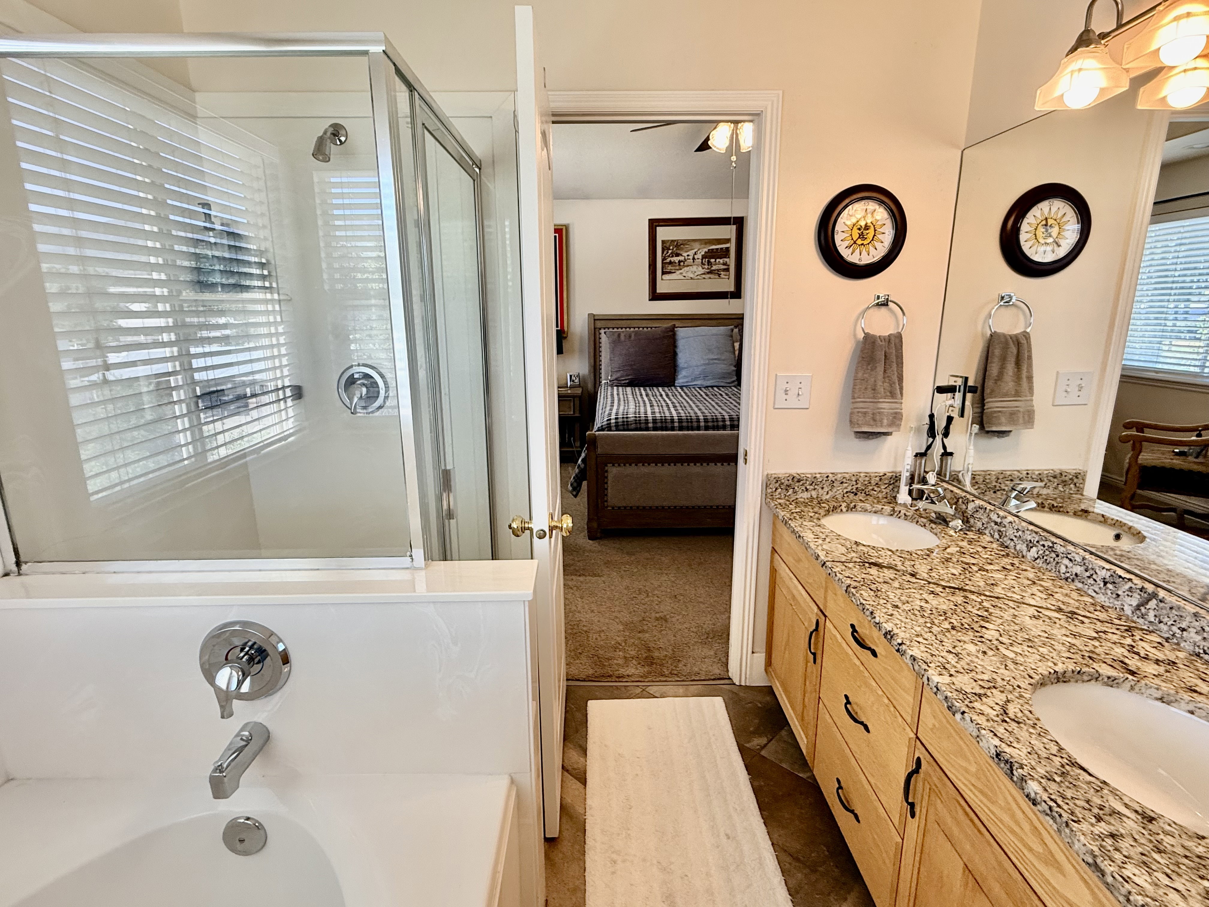 Bathroom featuring a dual-sink vanity with a stone-finish countertop, wood cabinetry, and a mirrored wall