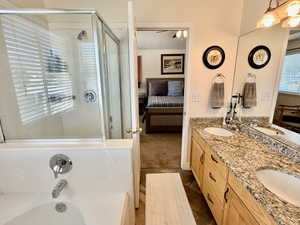 Bathroom featuring a dual-sink vanity with a stone-finish countertop, wood cabinetry, and a mirrored wall