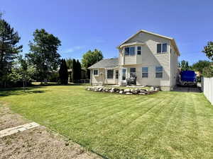 Expansive backyard featuring a manicured lawn, established trees, and a patio area