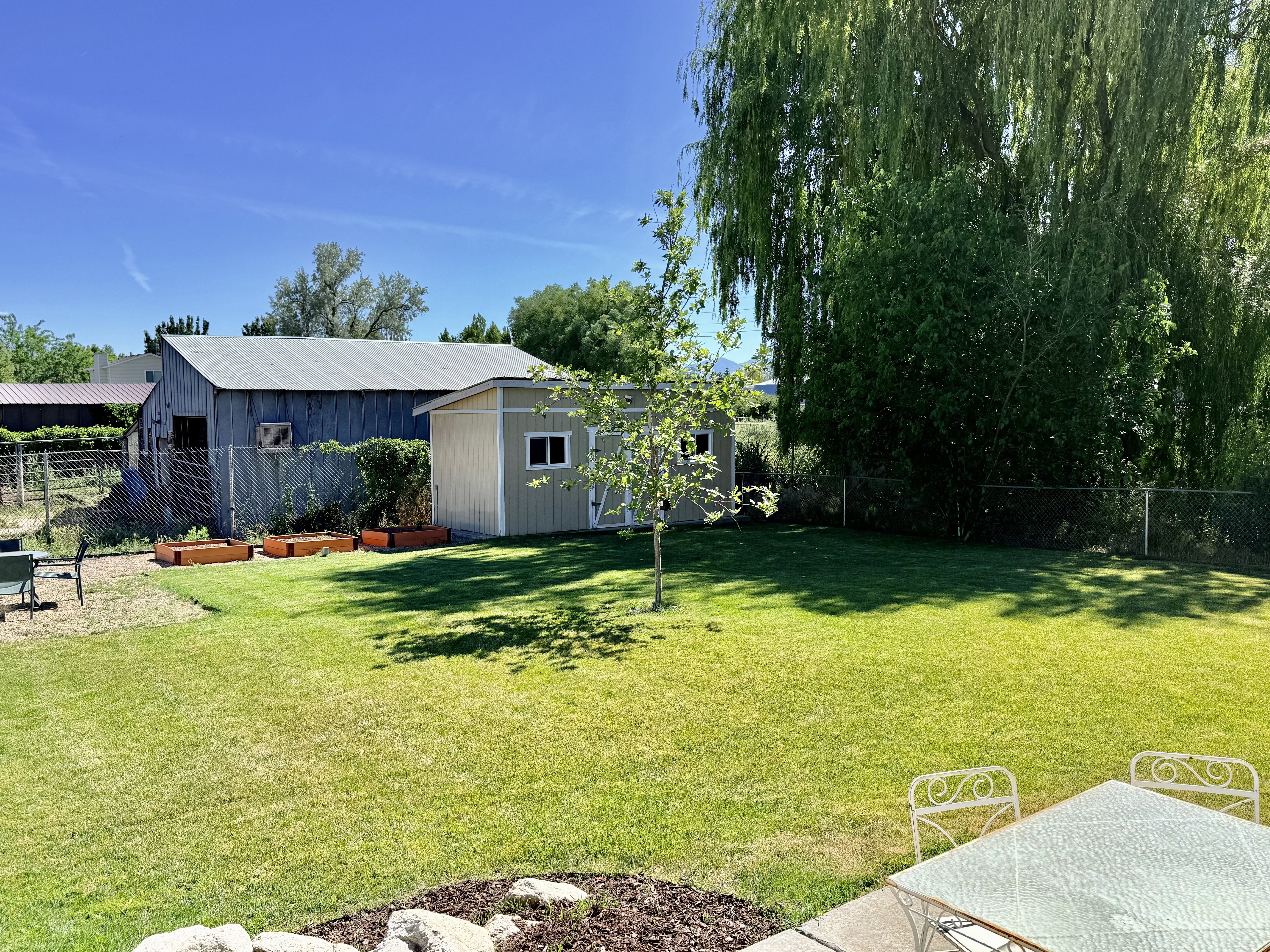 Spacious backyard featuring a manicured lawn, a detached storage shed, and a large barn structure
