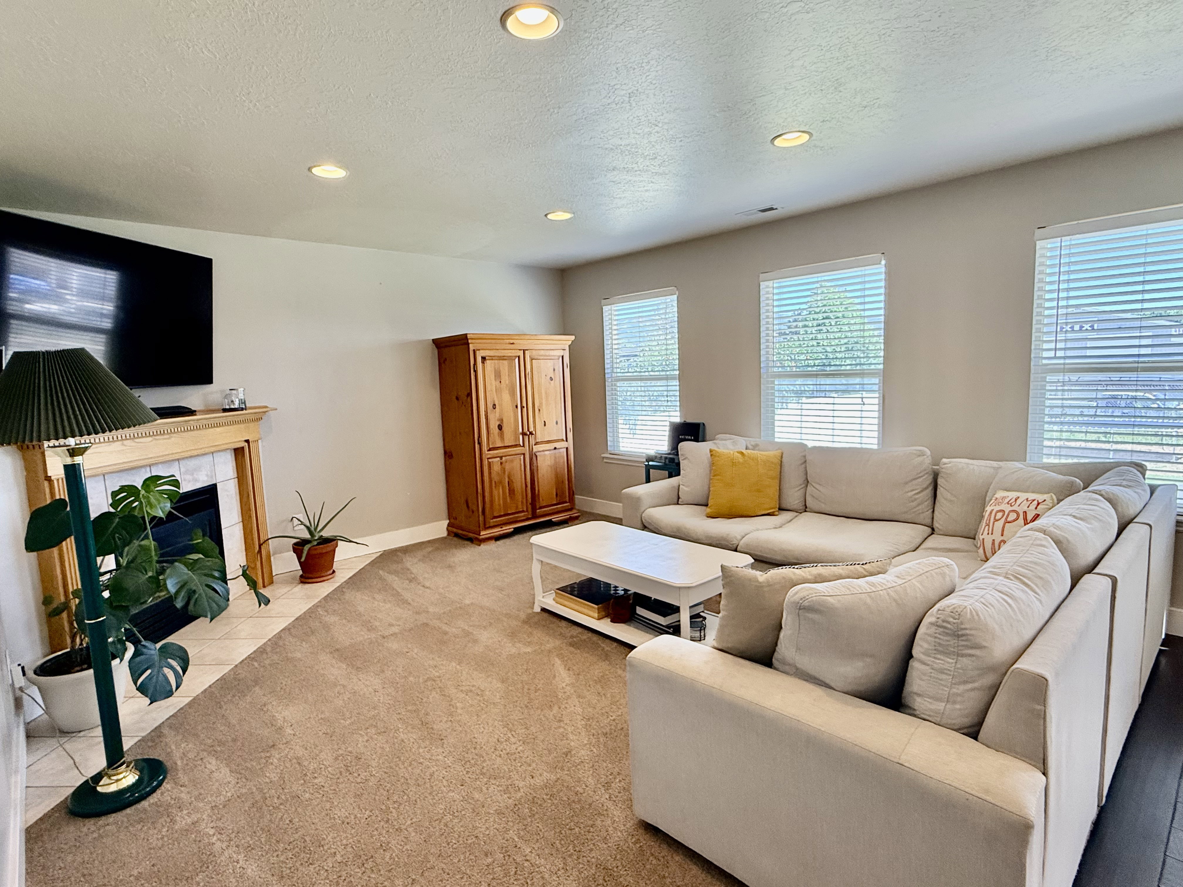 Living space featuring recessed lighting, a fireplace with a light wood mantel and tile surround, multiple windows with blinds, and carpet flooring