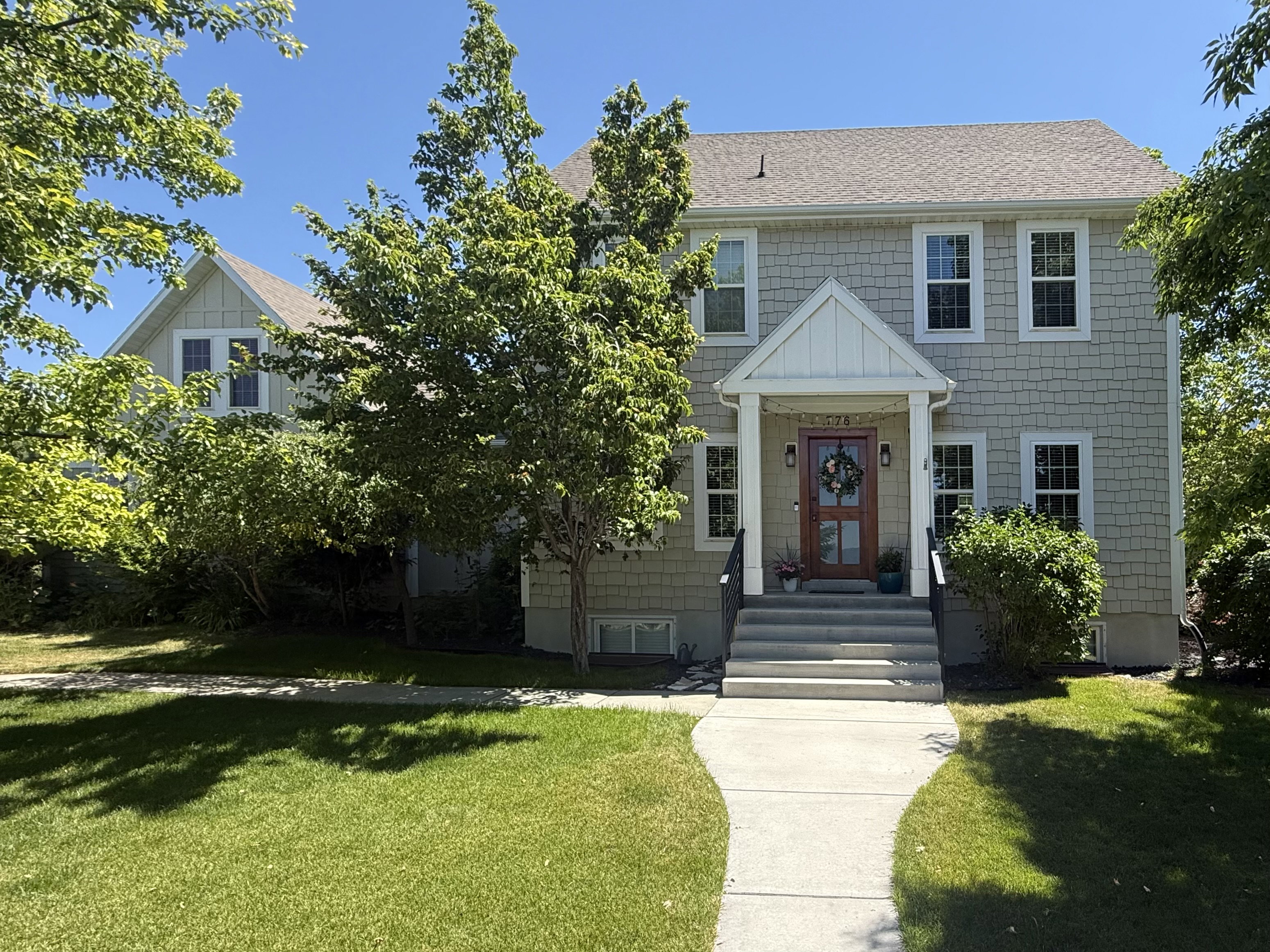 Craftsman-style home featuring shake siding, a covered entry porch with white columns, and a rich wood-finish front door