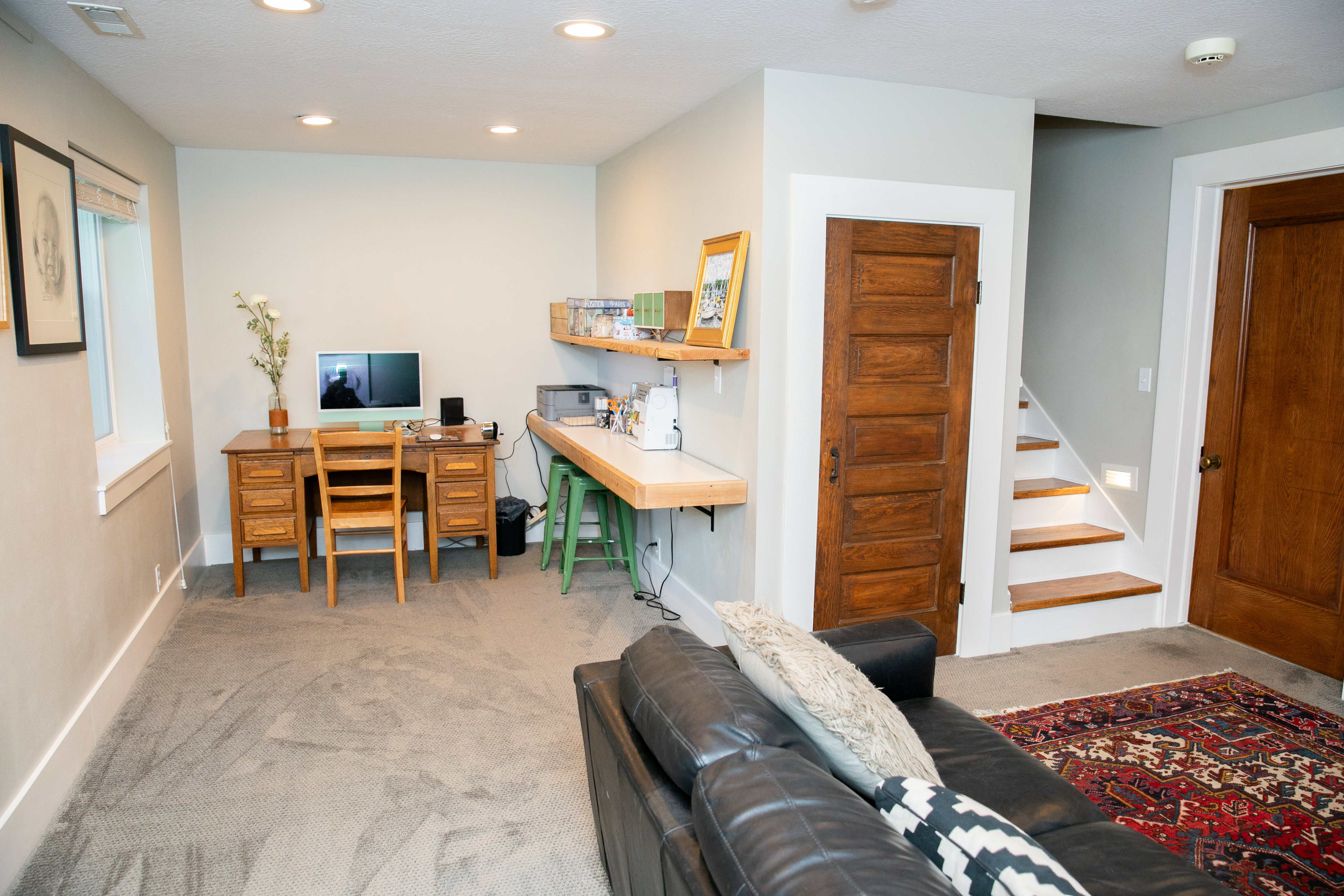 Carpeted living space featuring recessed lighting, a built-in wood-finish desk, and a built-in light wood-finish countertop with open shelving