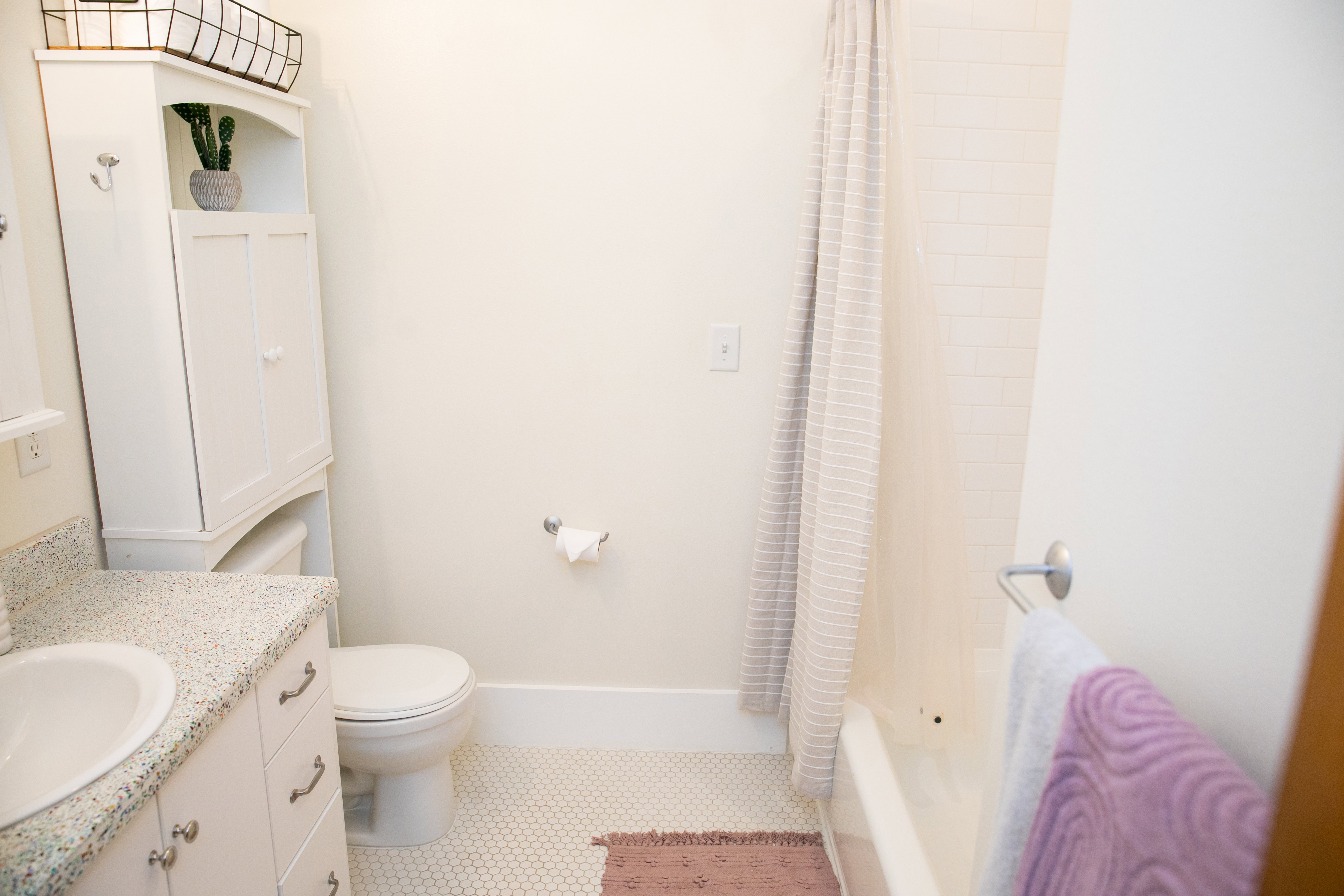 Bathroom featuring a white vanity with a speckled countertop and an undermount sink