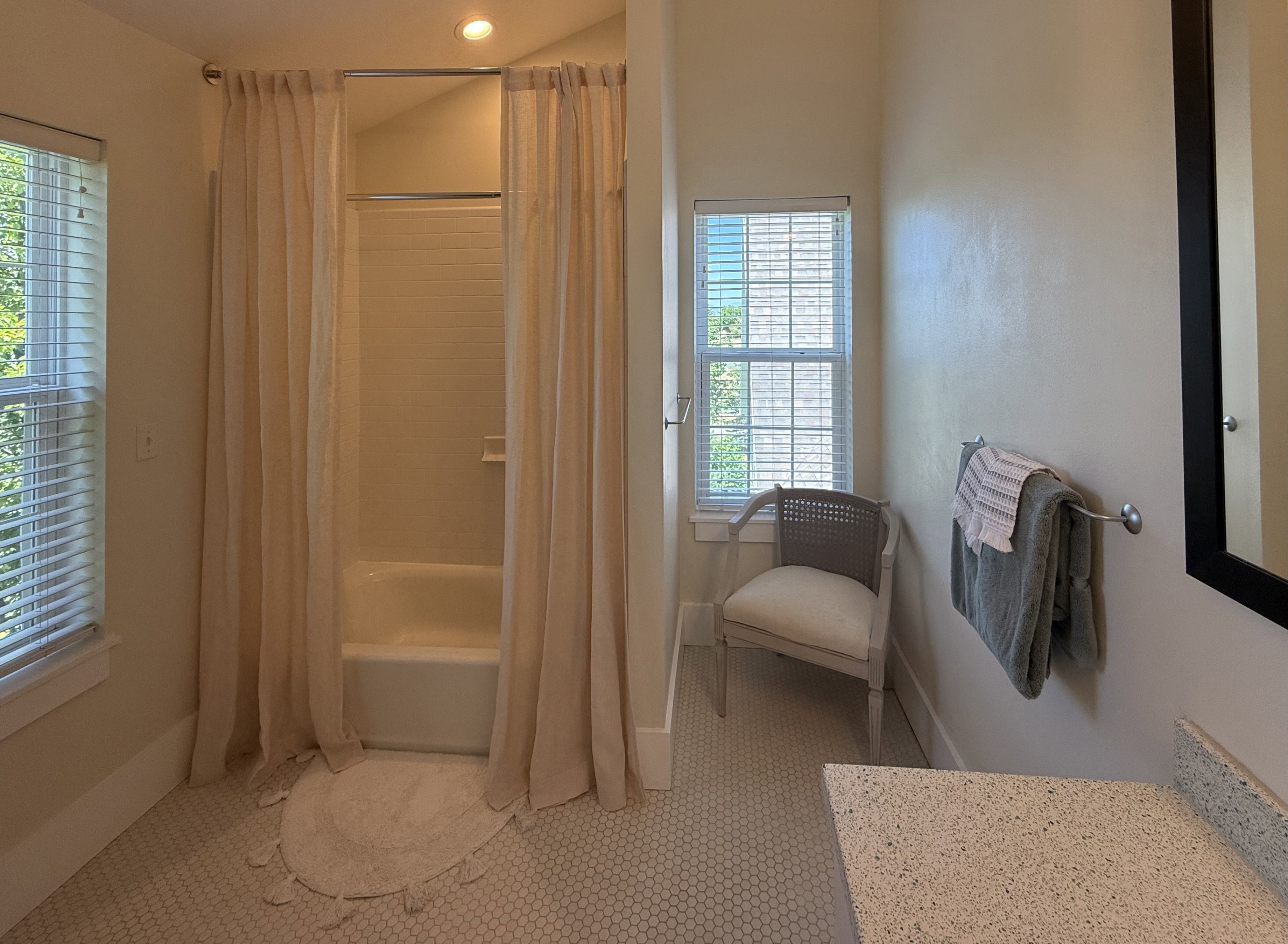 Bathroom featuring a tub/shower combination with tile surround, a window with horizontal blinds, and mosaic tile flooring