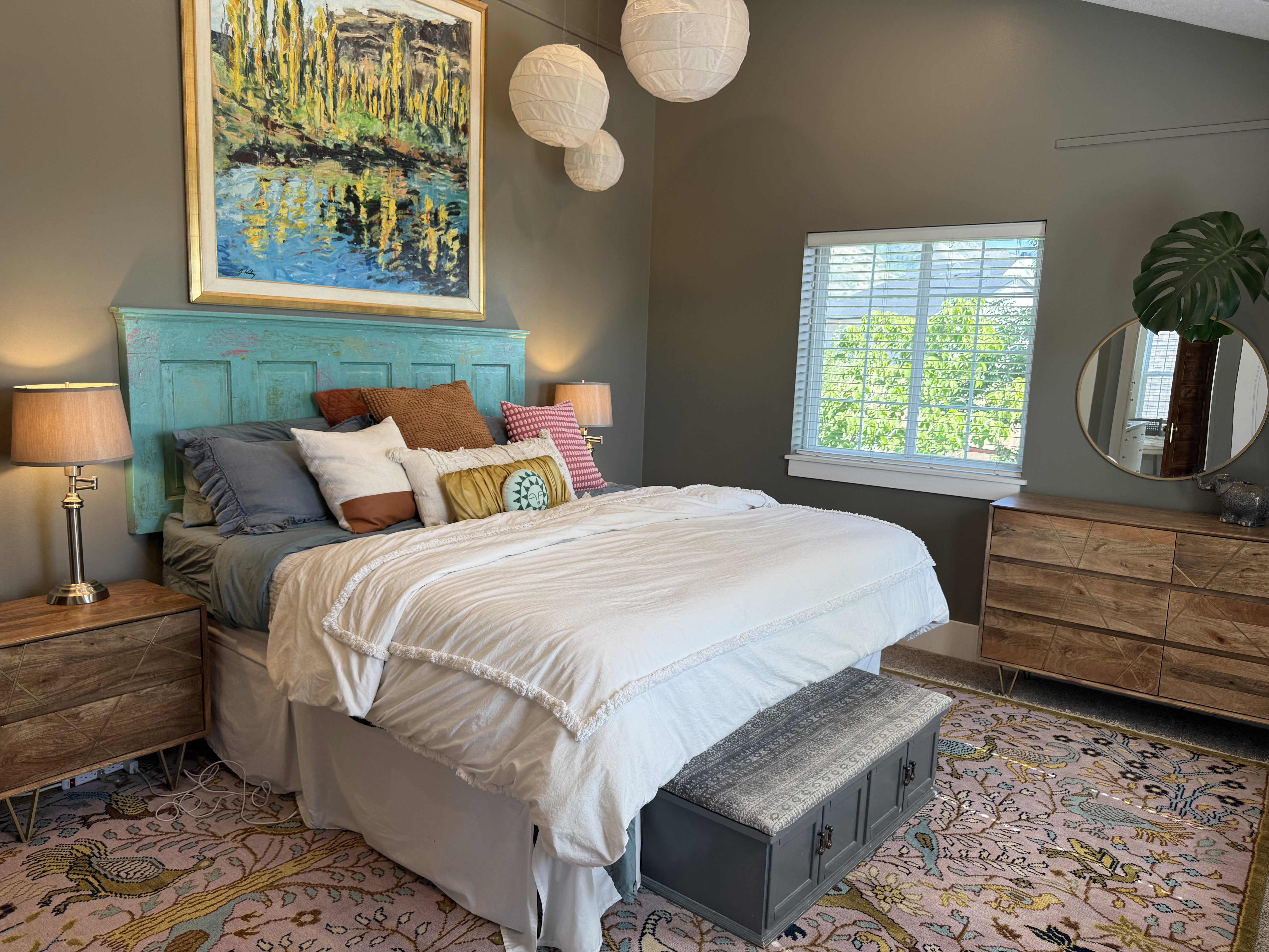 Vaulted ceilings and a large window illuminate this bedroom, featuring a unique teal headboard