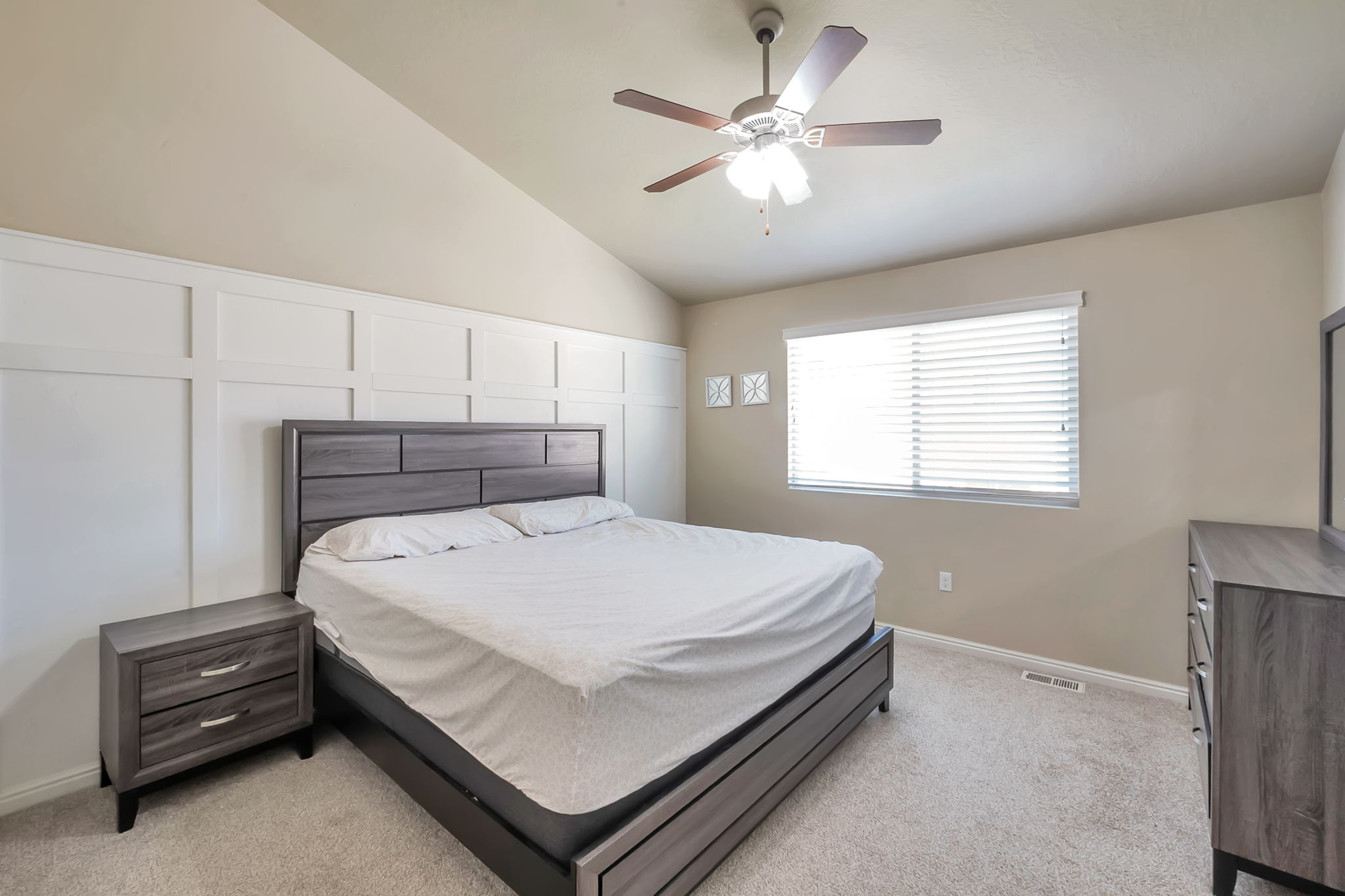 Bedroom featuring vaulted ceilings and a white accent wall with panel molding
