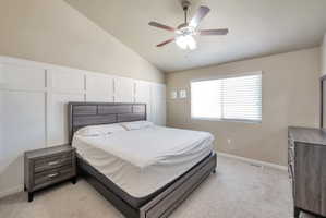Bedroom featuring vaulted ceilings and a white accent wall with panel molding