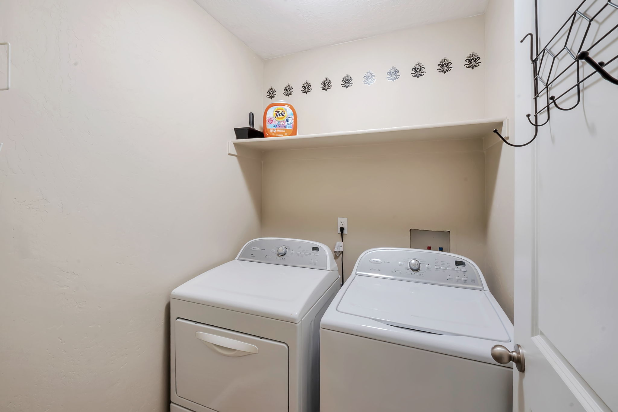 Dedicated laundry area featuring a built-in shelf, neutral wall tones, and a wall-mounted rack