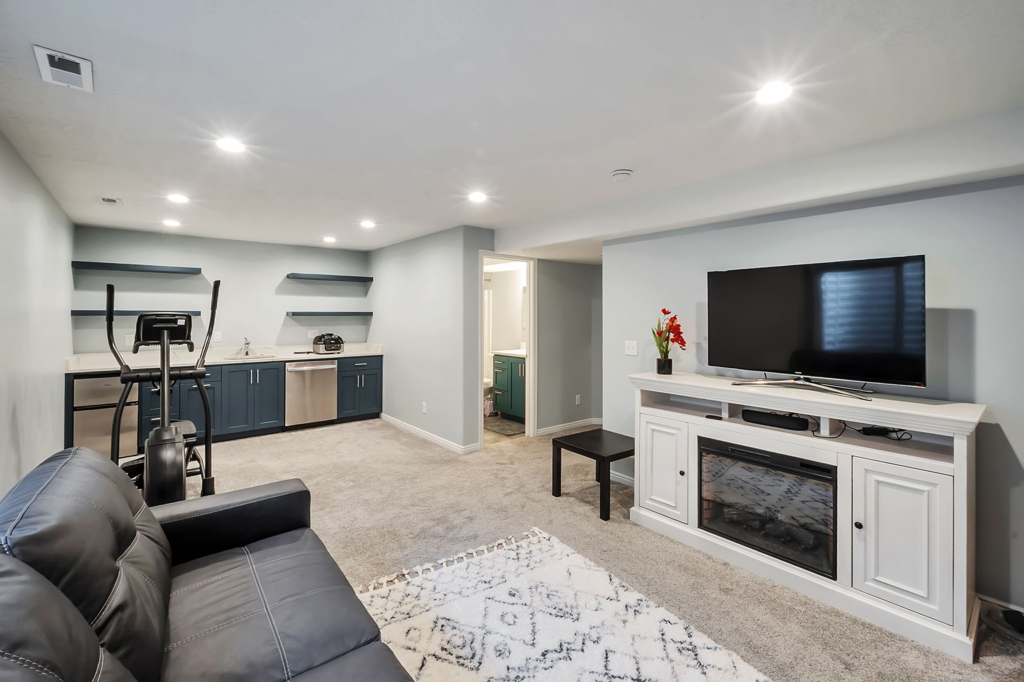 Carpeted recreation room featuring recessed lighting and a built-in media console with an electric fireplace