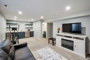 Carpeted recreation room featuring recessed lighting and a built-in media console with an electric fireplace