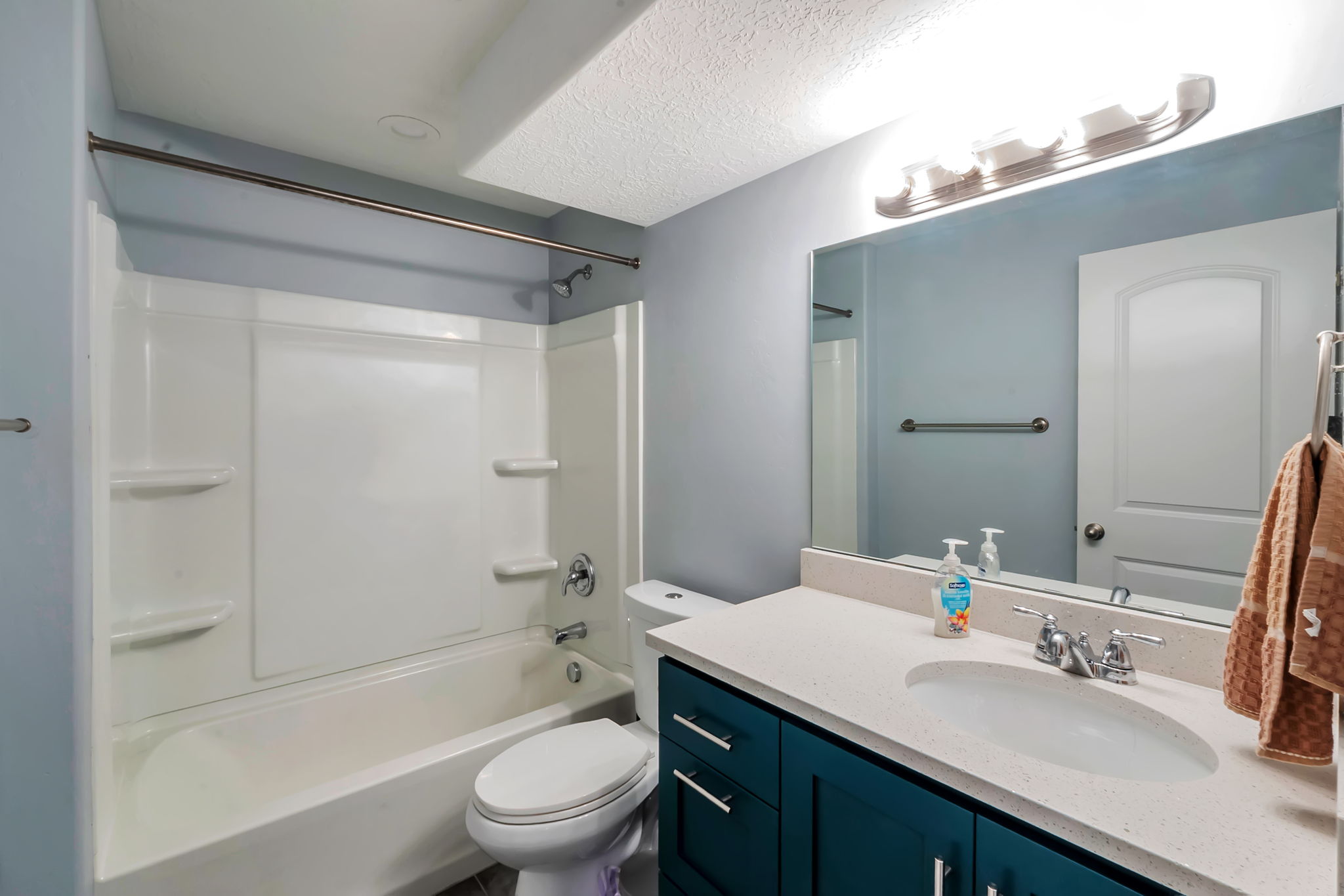 Full bathroom featuring a single vanity with integrated sink, stone-finish countertop, and teal cabinetry
