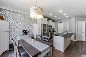 Open-concept kitchen and dining area featuring a decorative accent wall and an ornate drum pendant light