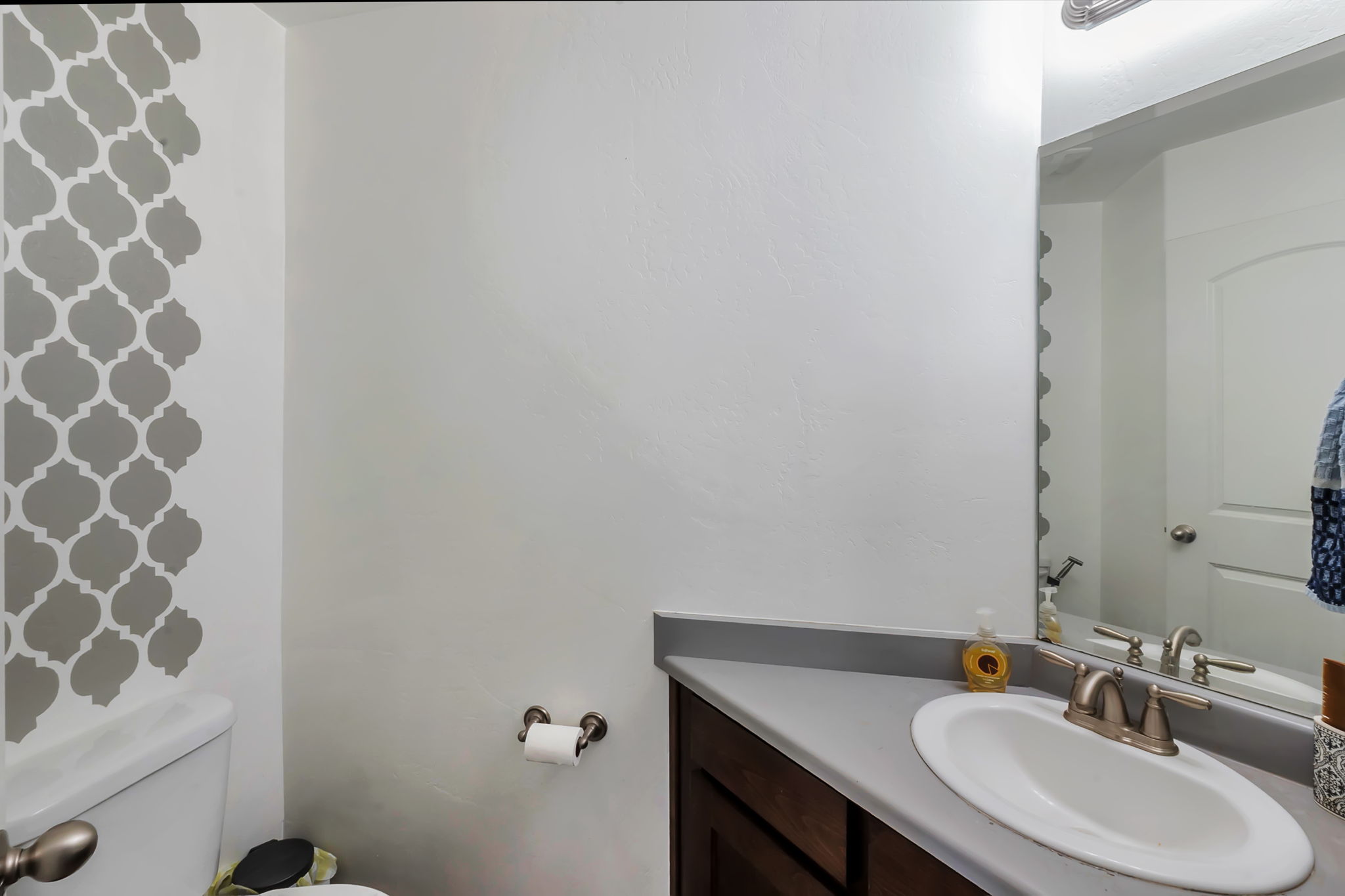 Bathroom vanity with a white oval sink, brushed nickel faucet, and a gray countertop