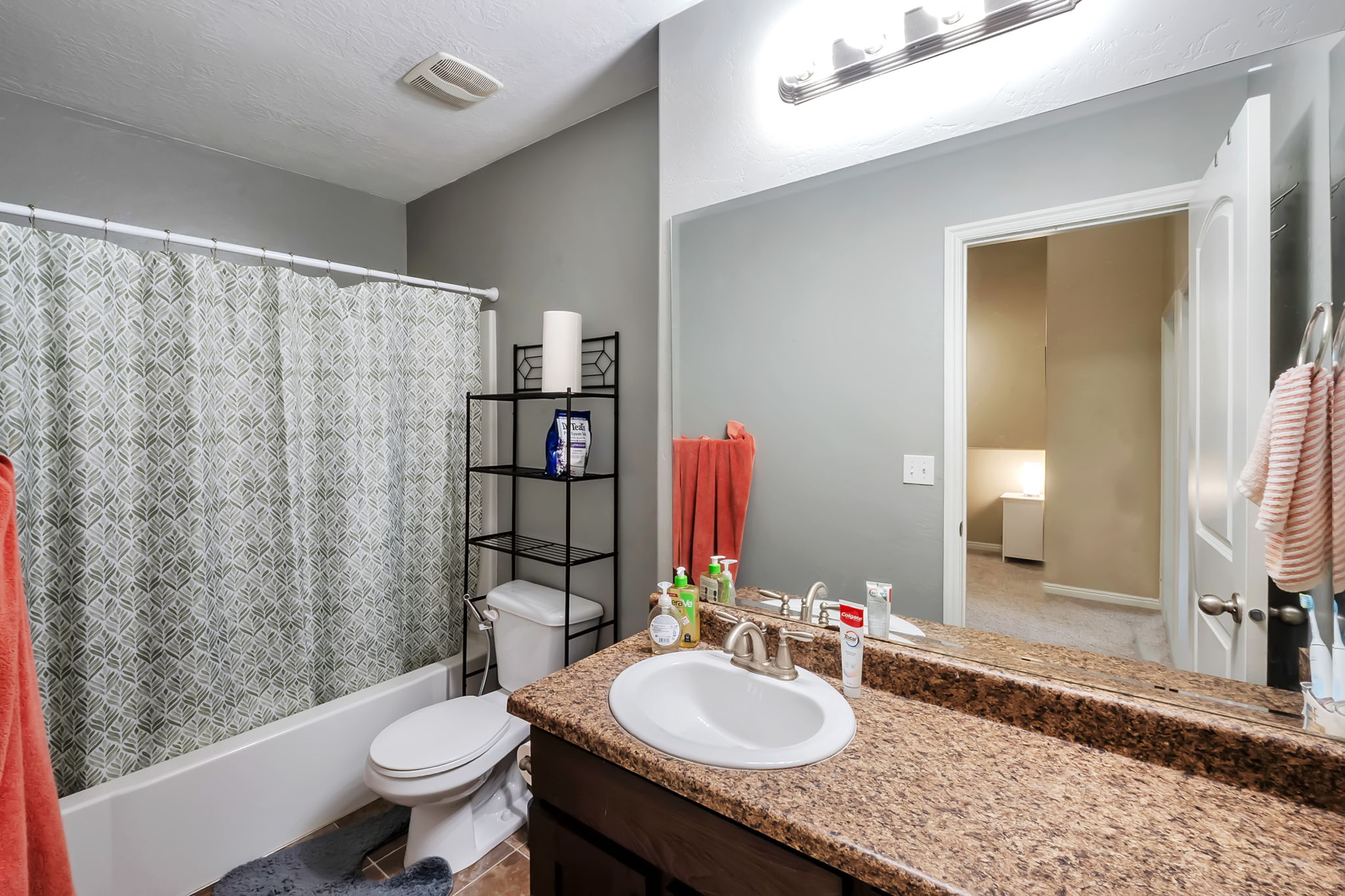 Full bathroom featuring a single vanity with a granite-finish countertop, brushed nickel faucet, and an integrated mirror