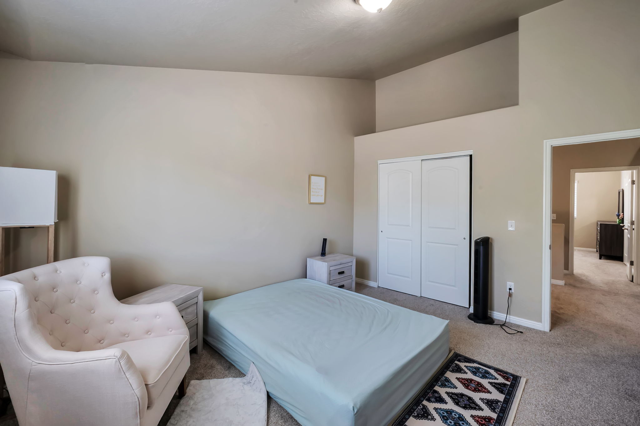 Carpeted room featuring a vaulted ceiling and neutral wall tones