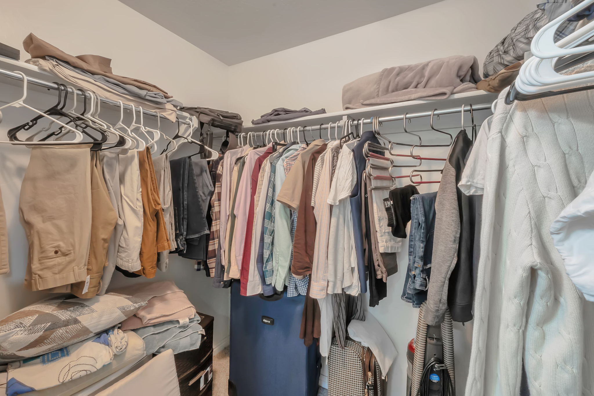 Walk-in closet featuring white walls, wire shelving, and chrome hanging rods