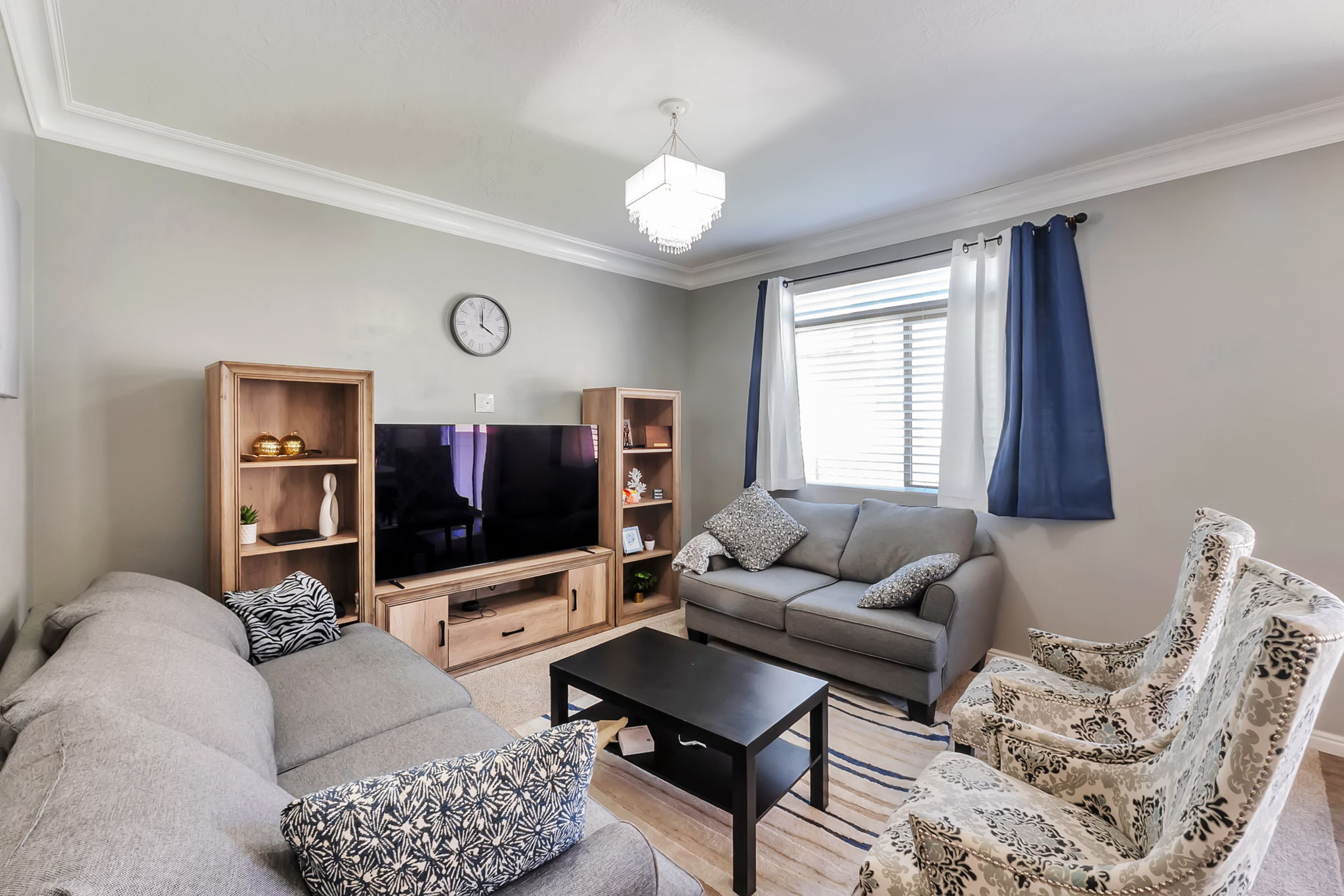 Living area featuring light gray walls, white crown molding, and wood-finish flooring