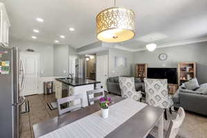 Open-concept common area featuring a kitchen island with dark stone countertop, recessed lighting, and crown molding