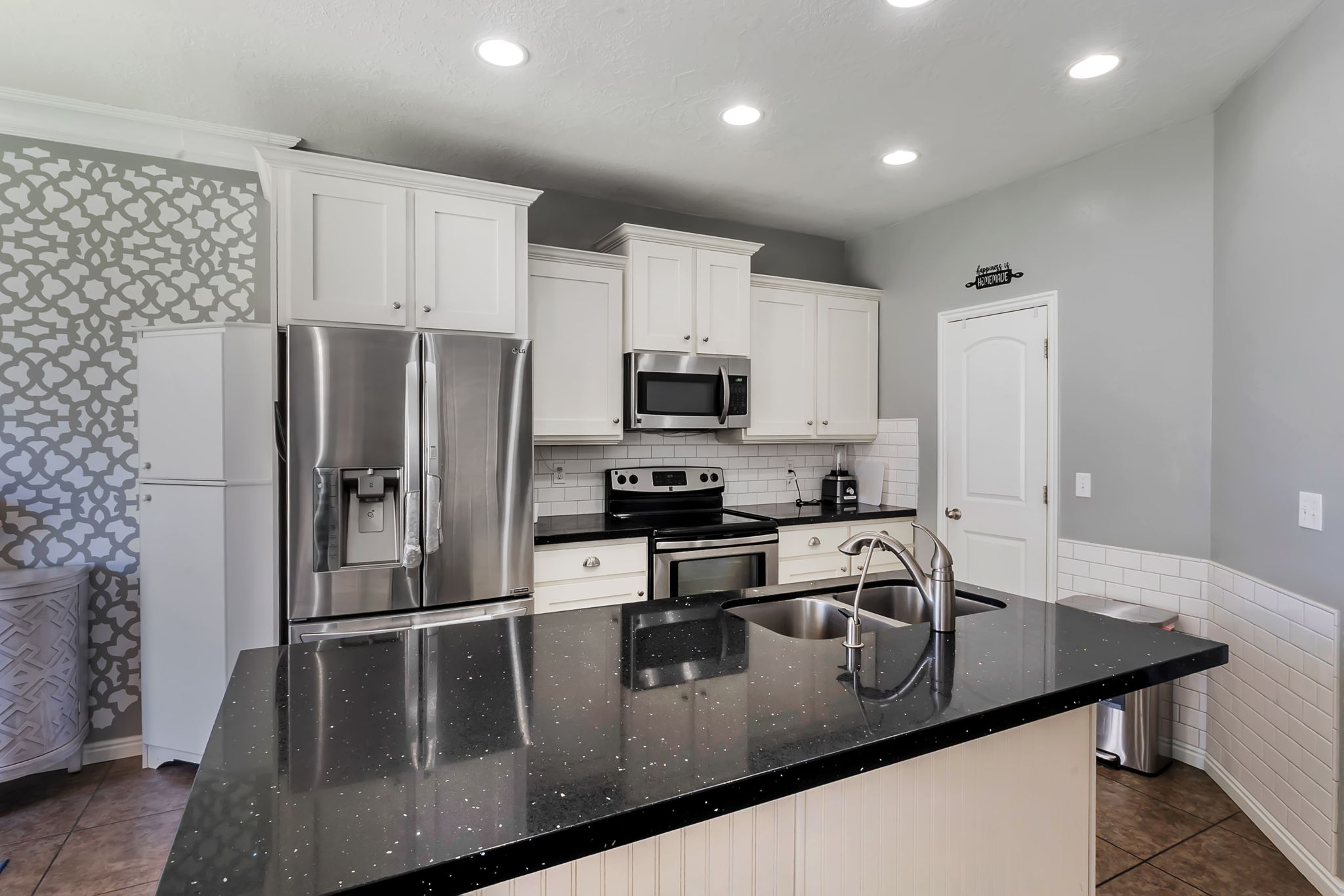Kitchen featuring an island with a double basin sink and a black speckled countertop