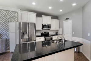 Kitchen featuring an island with a double basin sink and a black speckled countertop