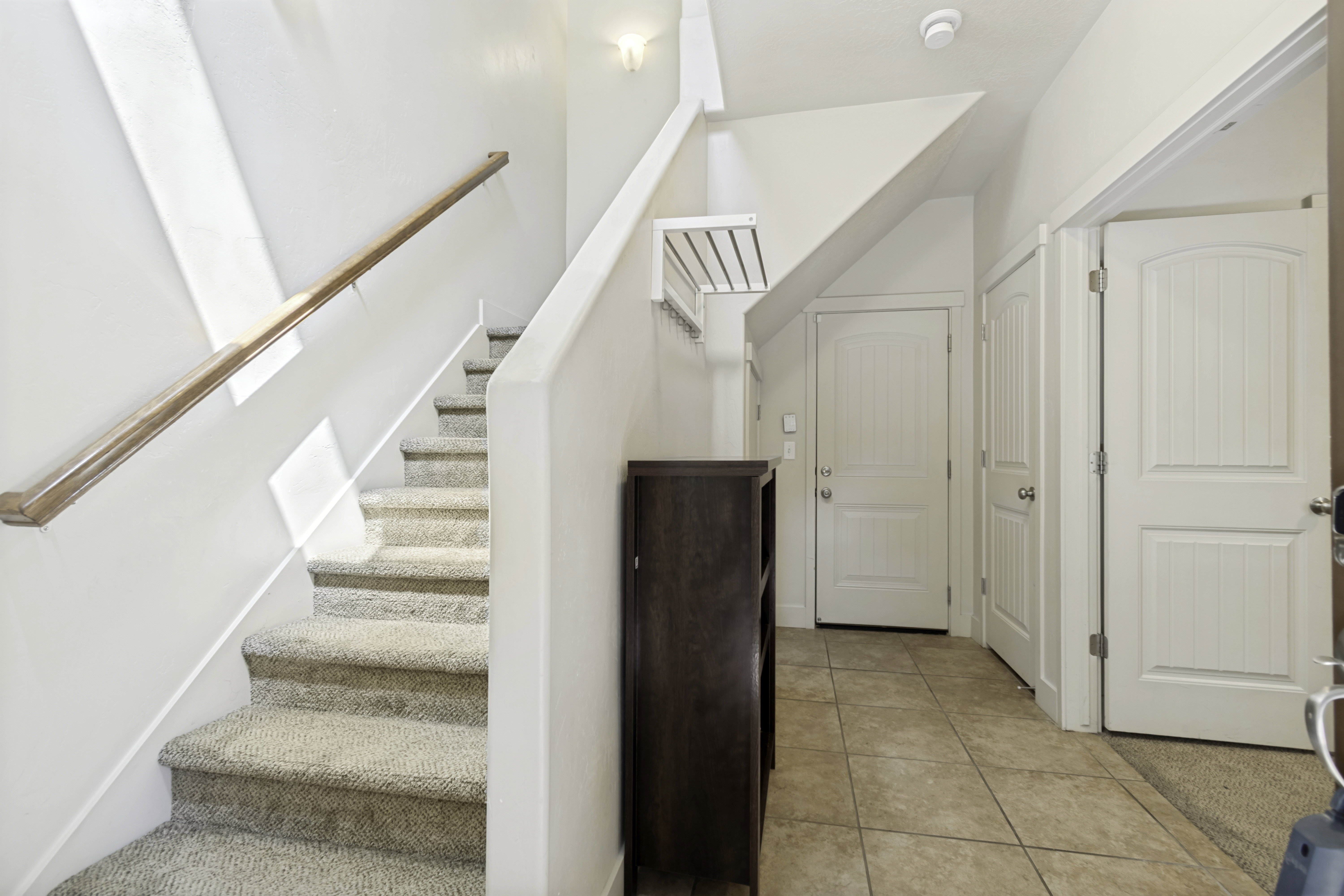 Entryway featuring tile flooring, white paneled doors, and a staircase with carpeted treads and a wood handrail
