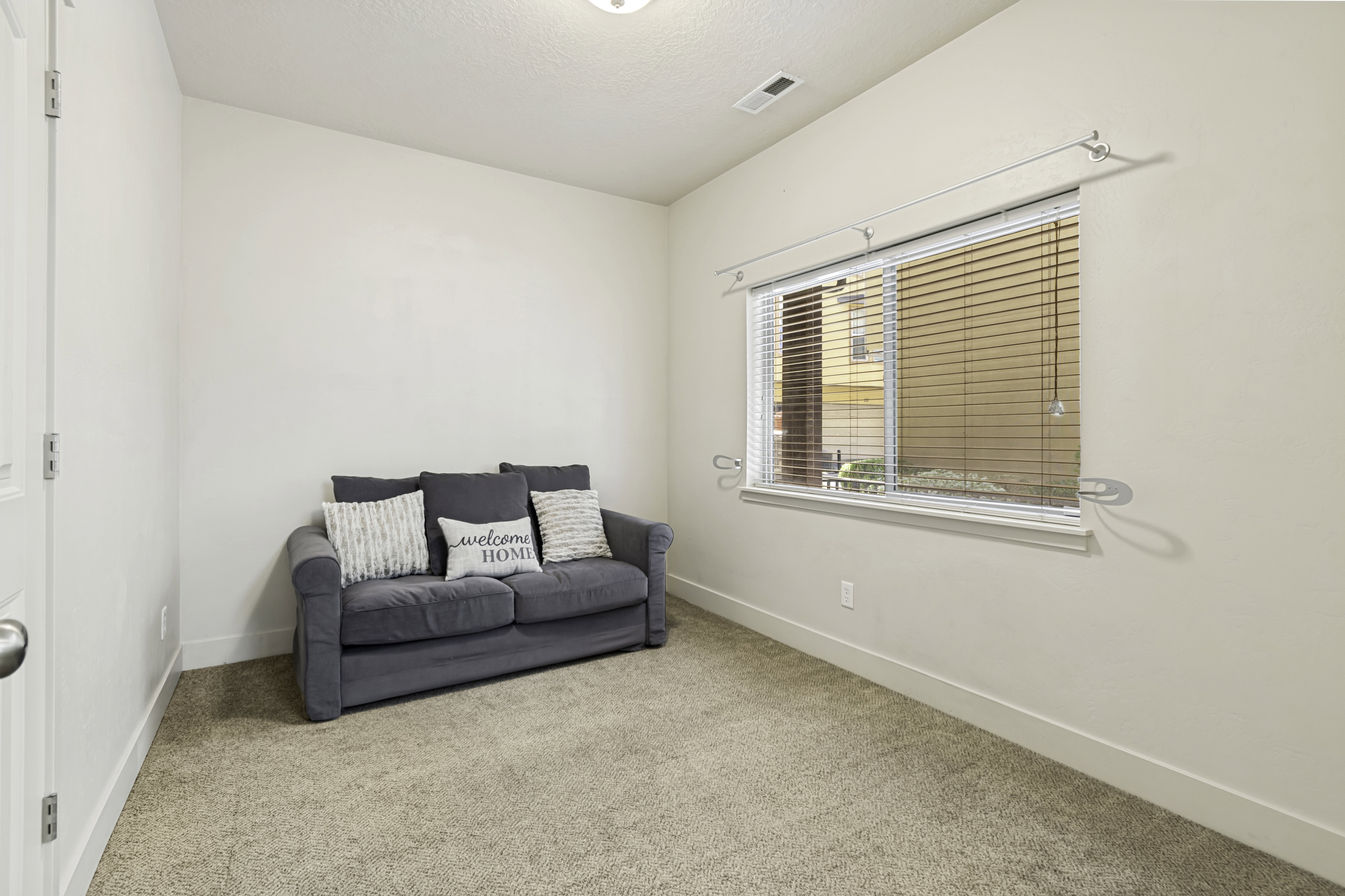 Carpeted room with a single window featuring horizontal blinds