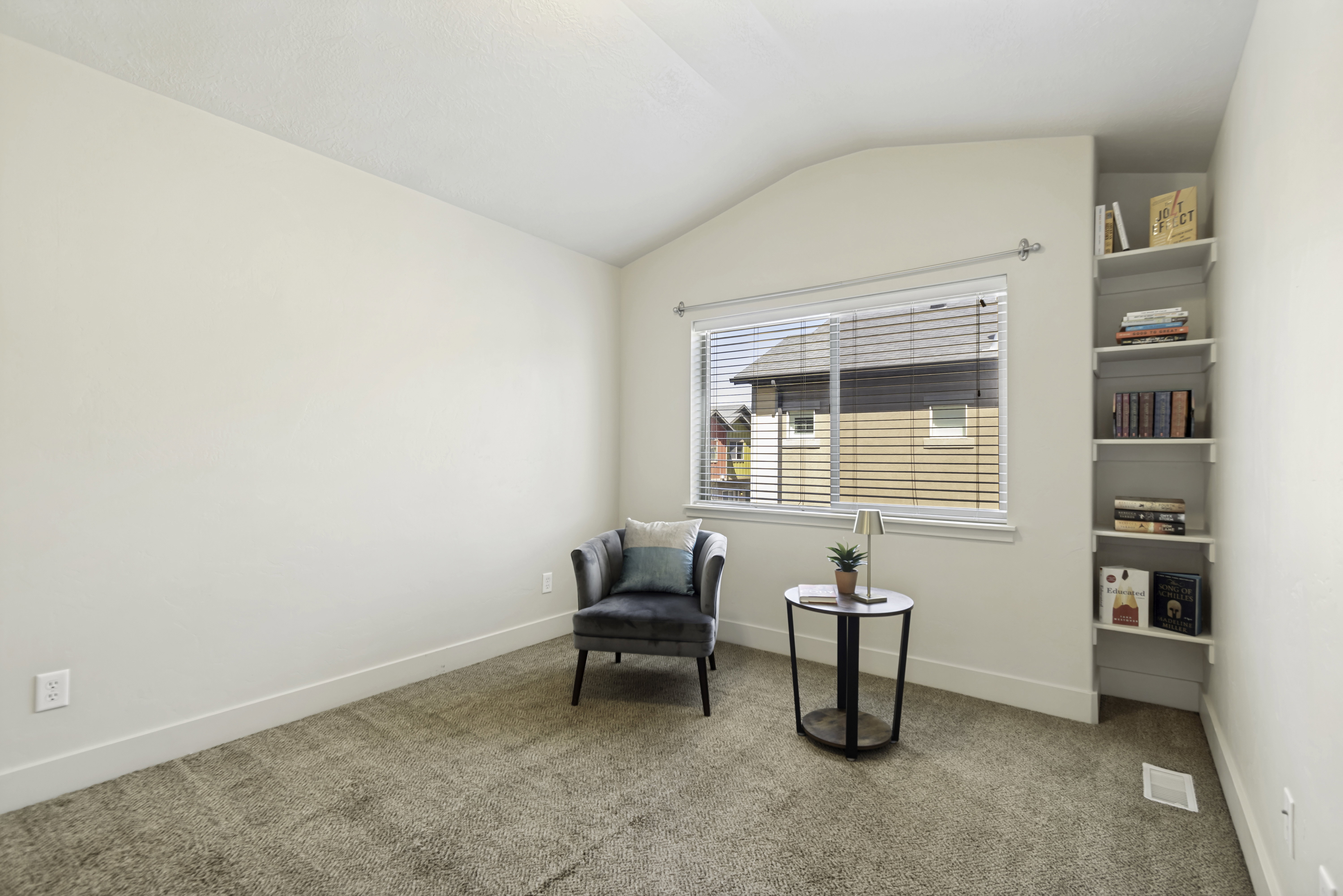Carpeted room featuring a window with horizontal blinds, built-in shelving, white baseboards, and neutral wall paint