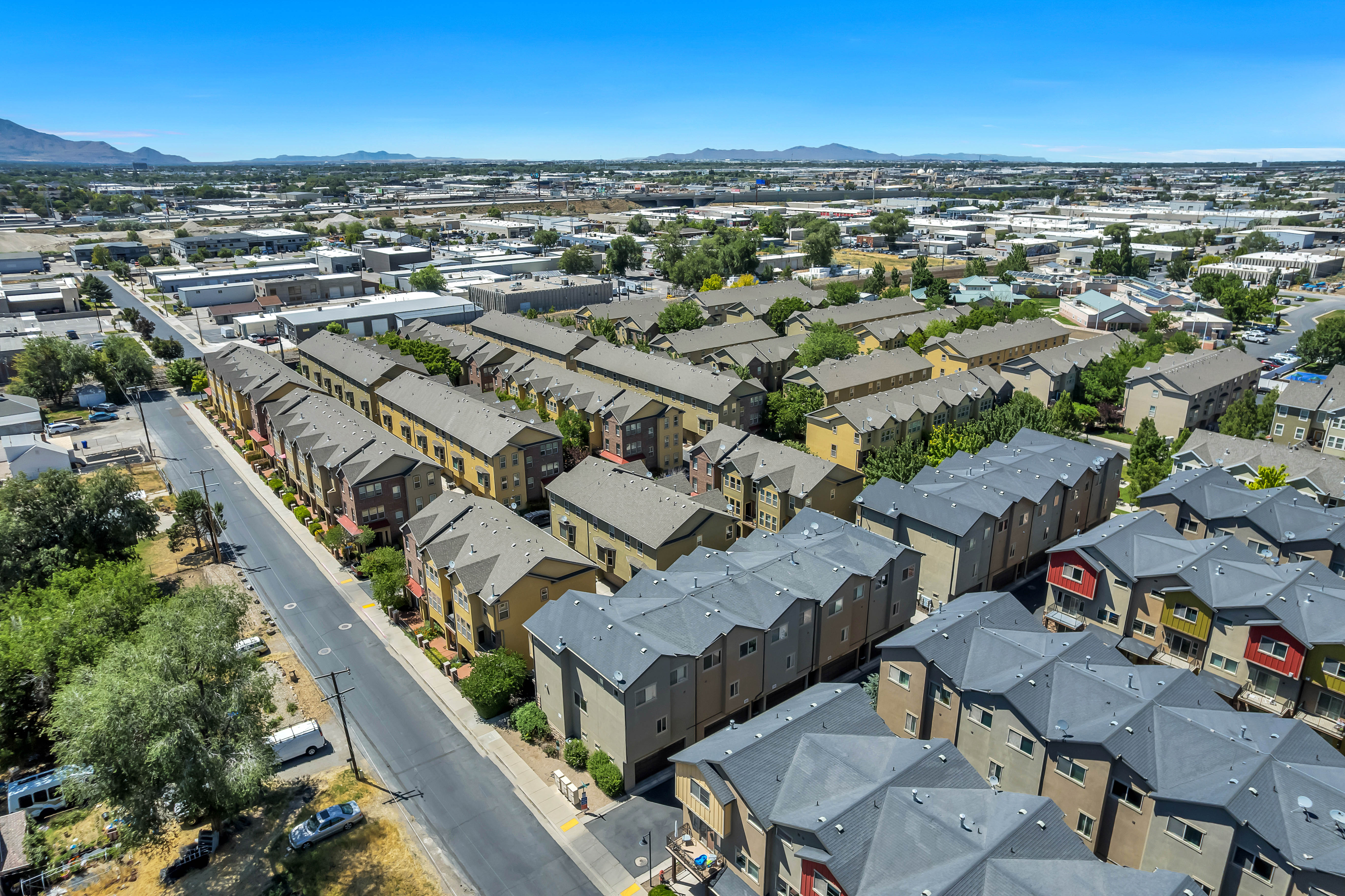 Contemporary multi-story townhomes featuring varied exterior finishes, individual balconies, and dark-toned roofing