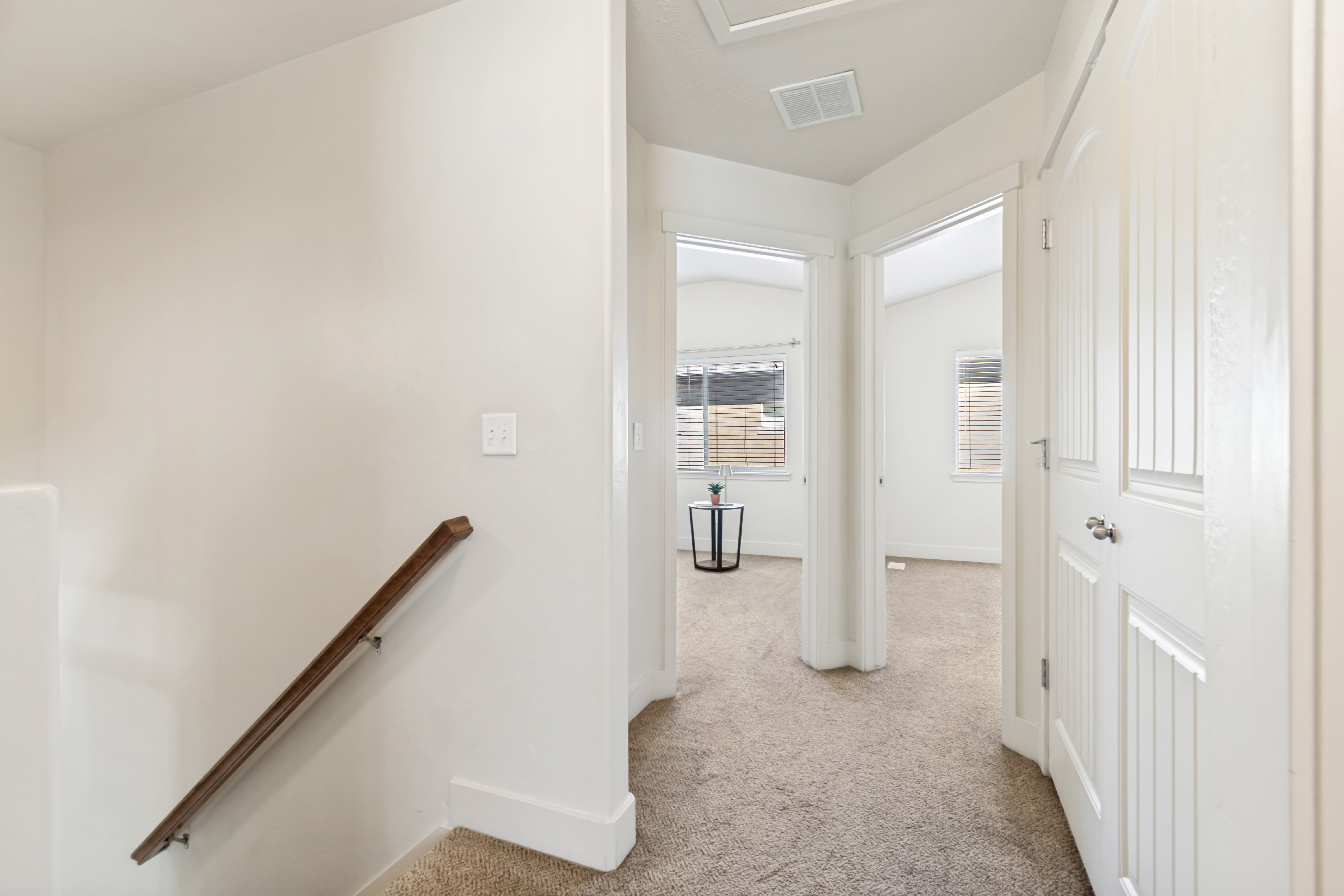 Neutral-toned corridor with plush carpeting, leading to multiple rooms