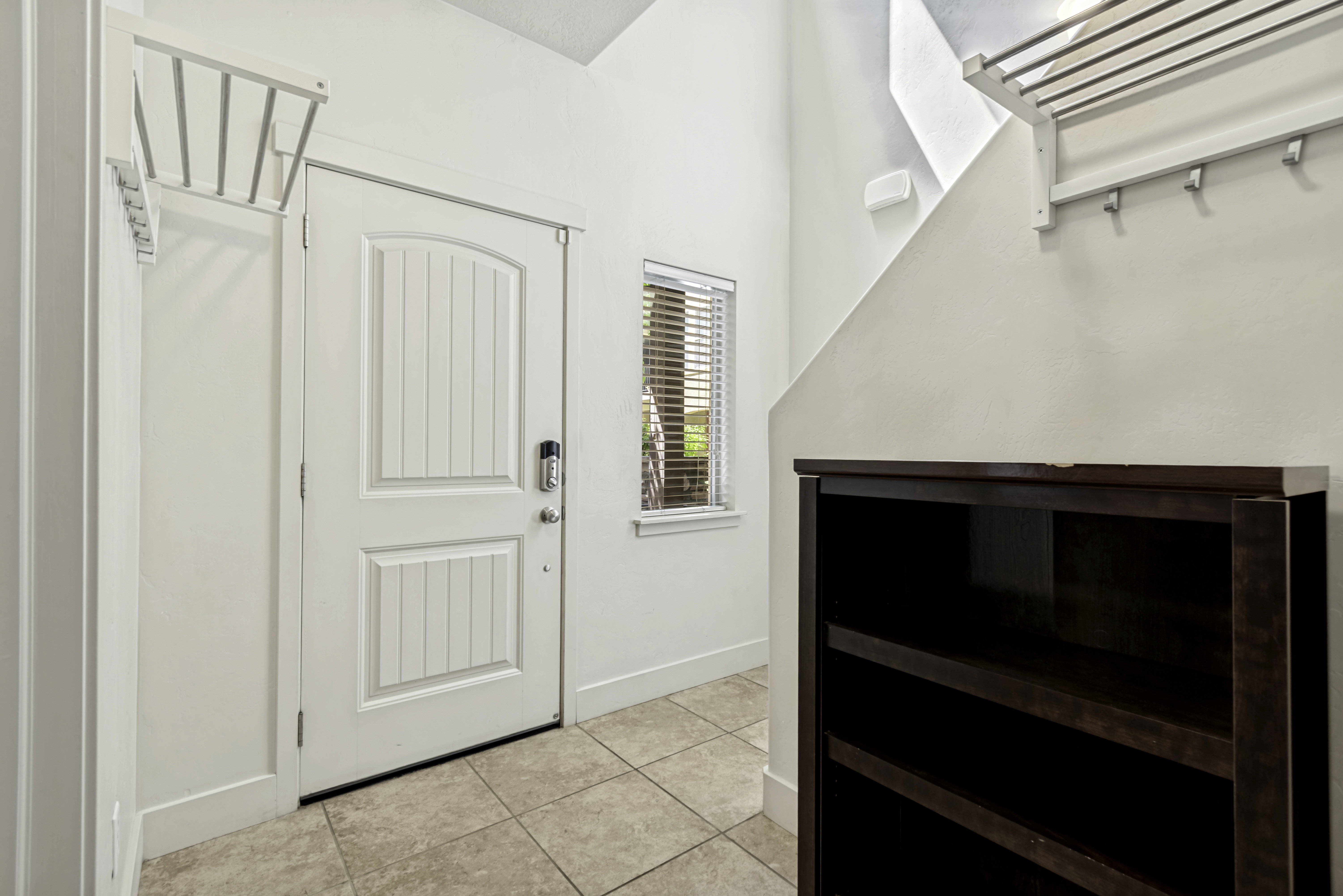 Entryway featuring a paneled door with smart lock, an adjacent window with horizontal blinds, and tile flooring