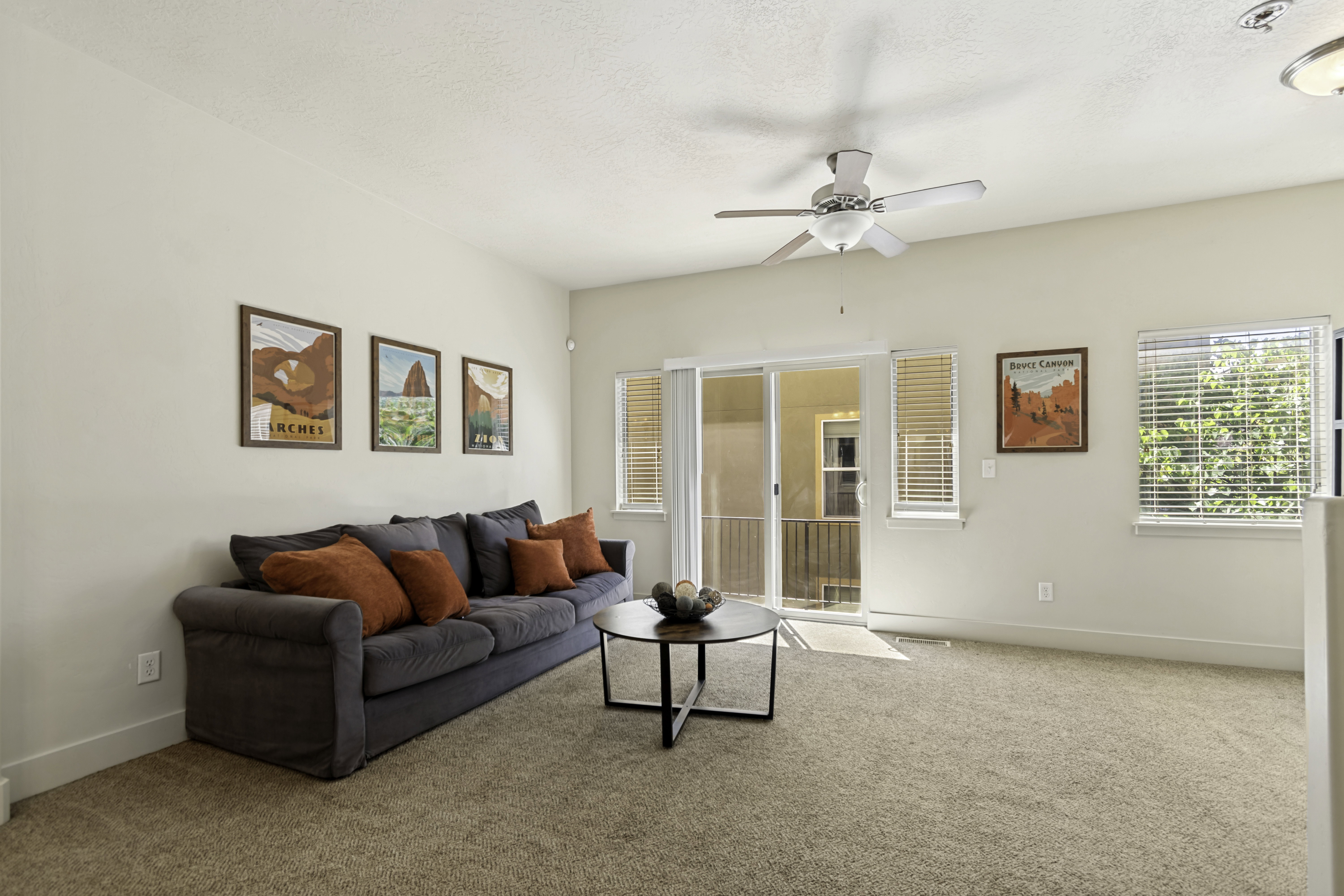 Carpeted living space featuring light-toned walls, a ceiling fan, and white trim