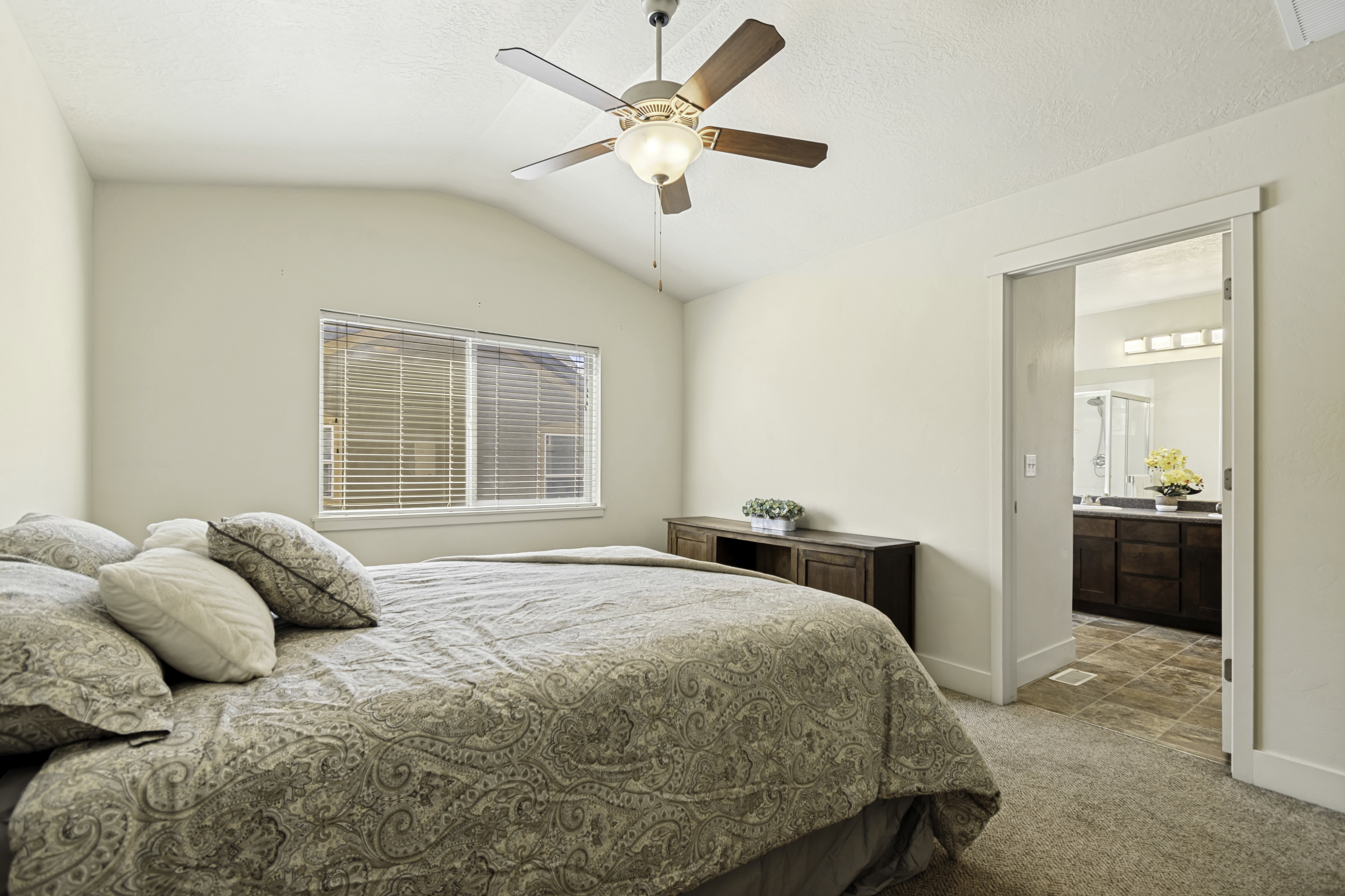 Vaulted ceiling bedroom featuring a ceiling fan with integrated lighting, window with blinds, and carpeted flooring