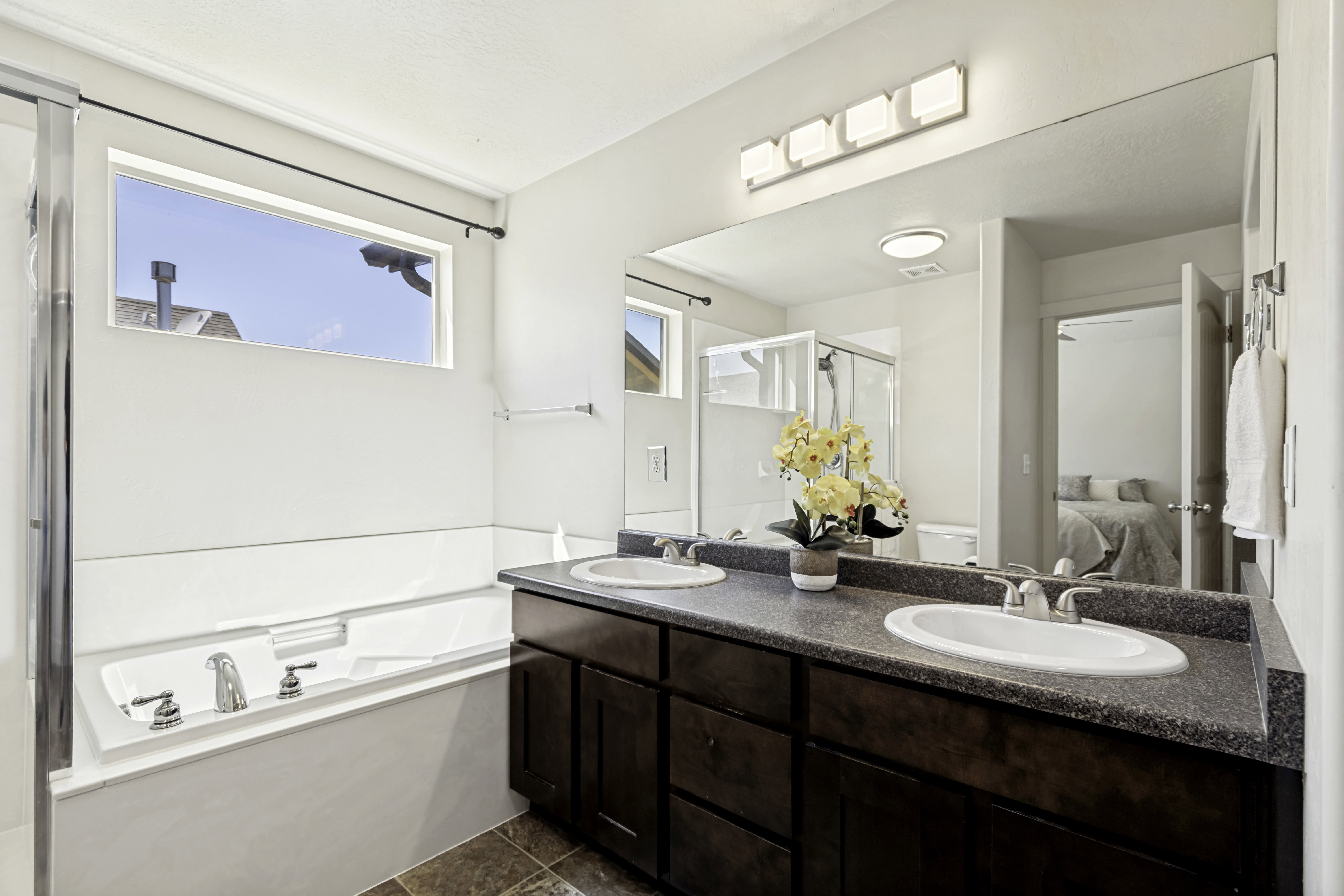Dual vanity with undermount sinks, a large wall-mounted mirror, and a contemporary four-light fixture