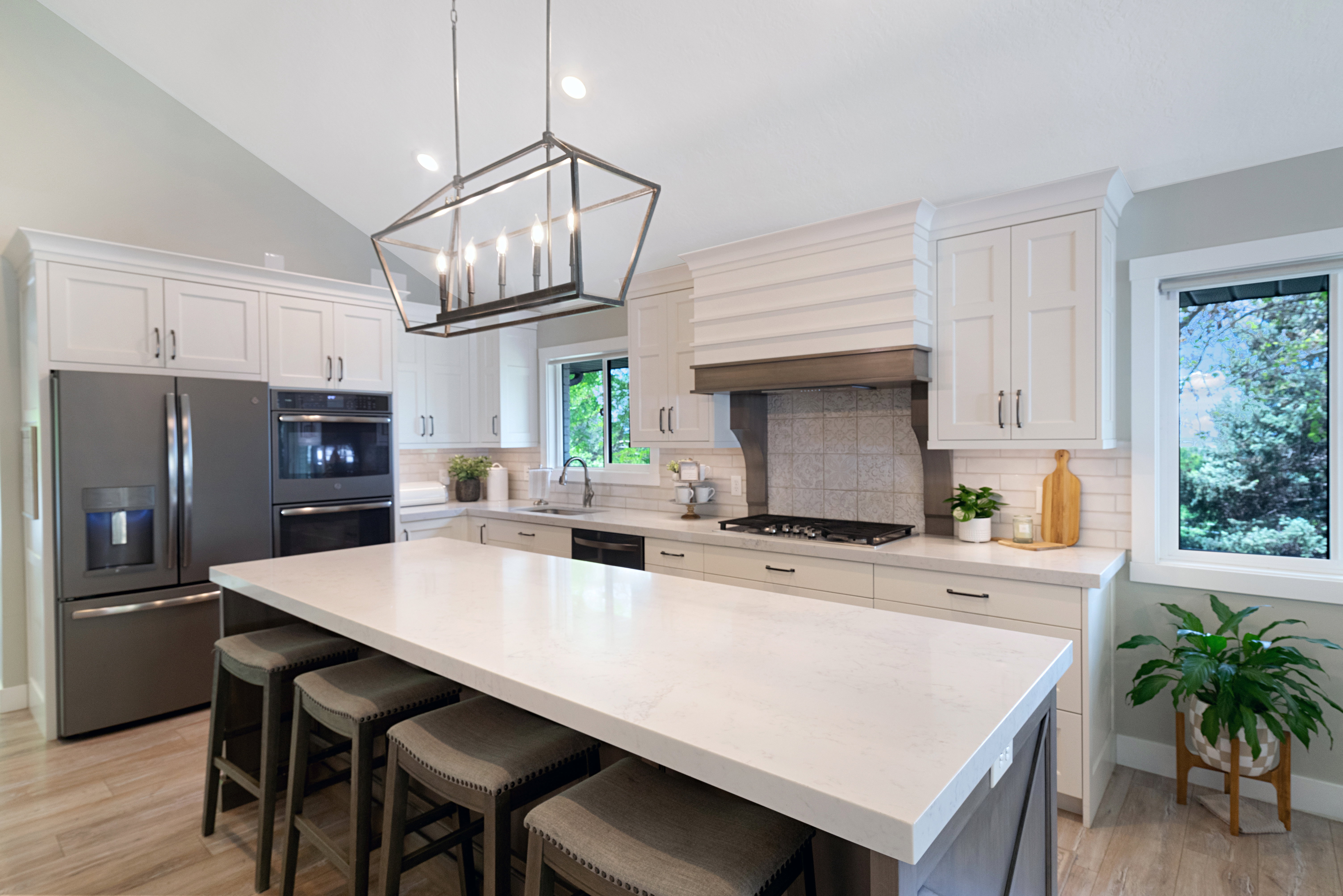 Kitchen featuring a large central island with seating, vaulted ceiling, wood-finish flooring, white cabinetry, and stainless steel appliances