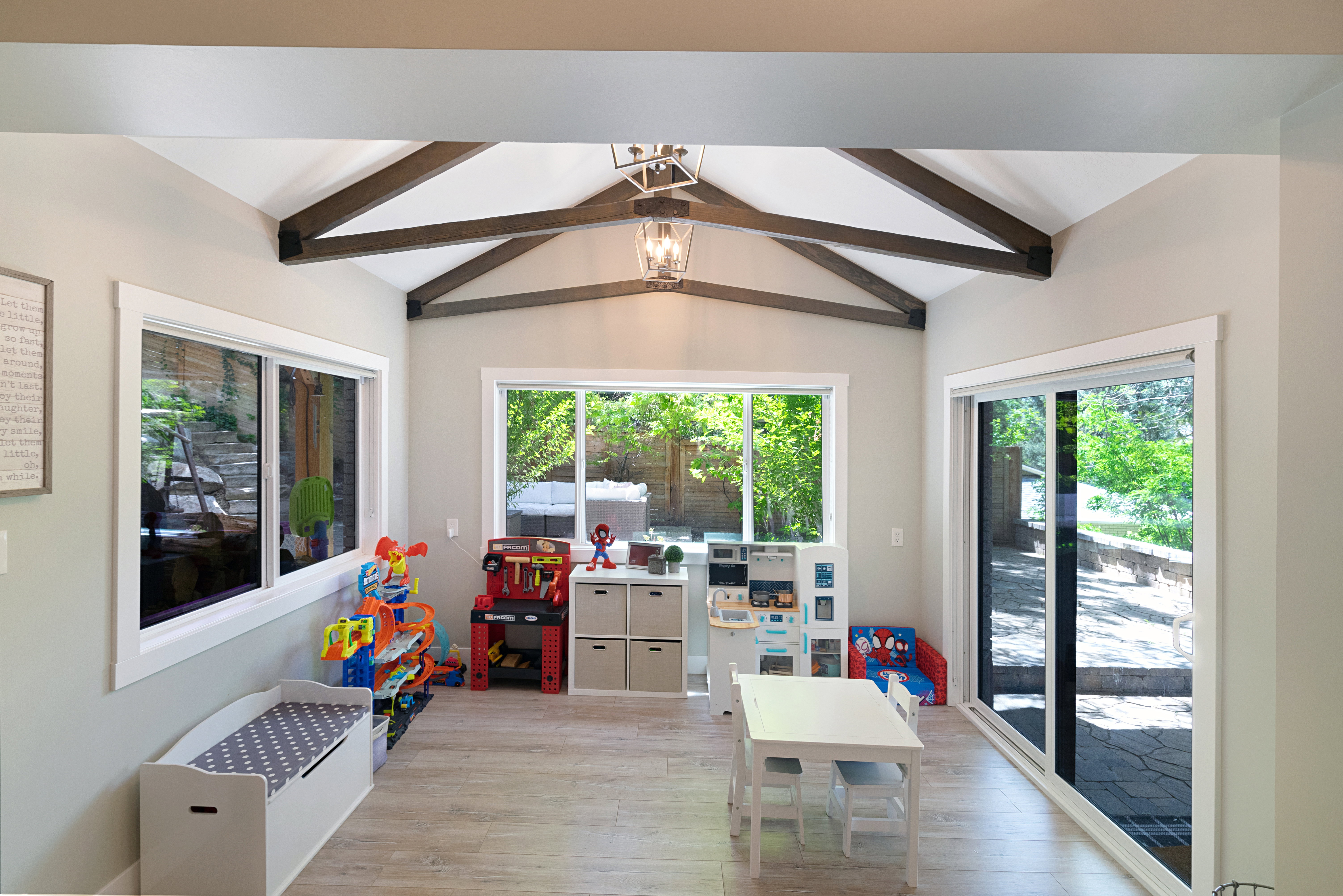 Vaulted ceiling with exposed wood beams, wood-finish flooring, recessed lighting, and large windows with white trim