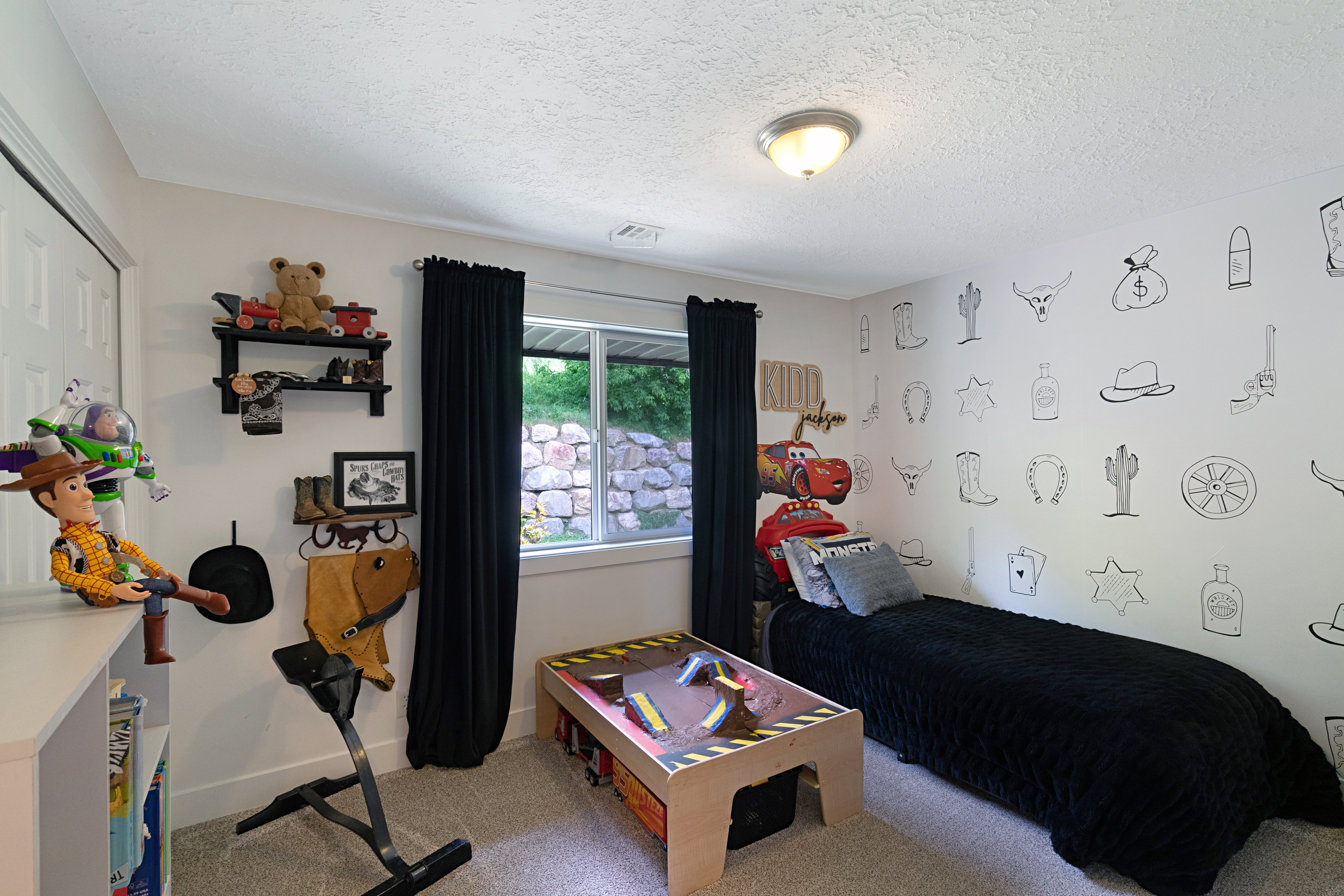 Carpeted room with a single window featuring black blackout curtains