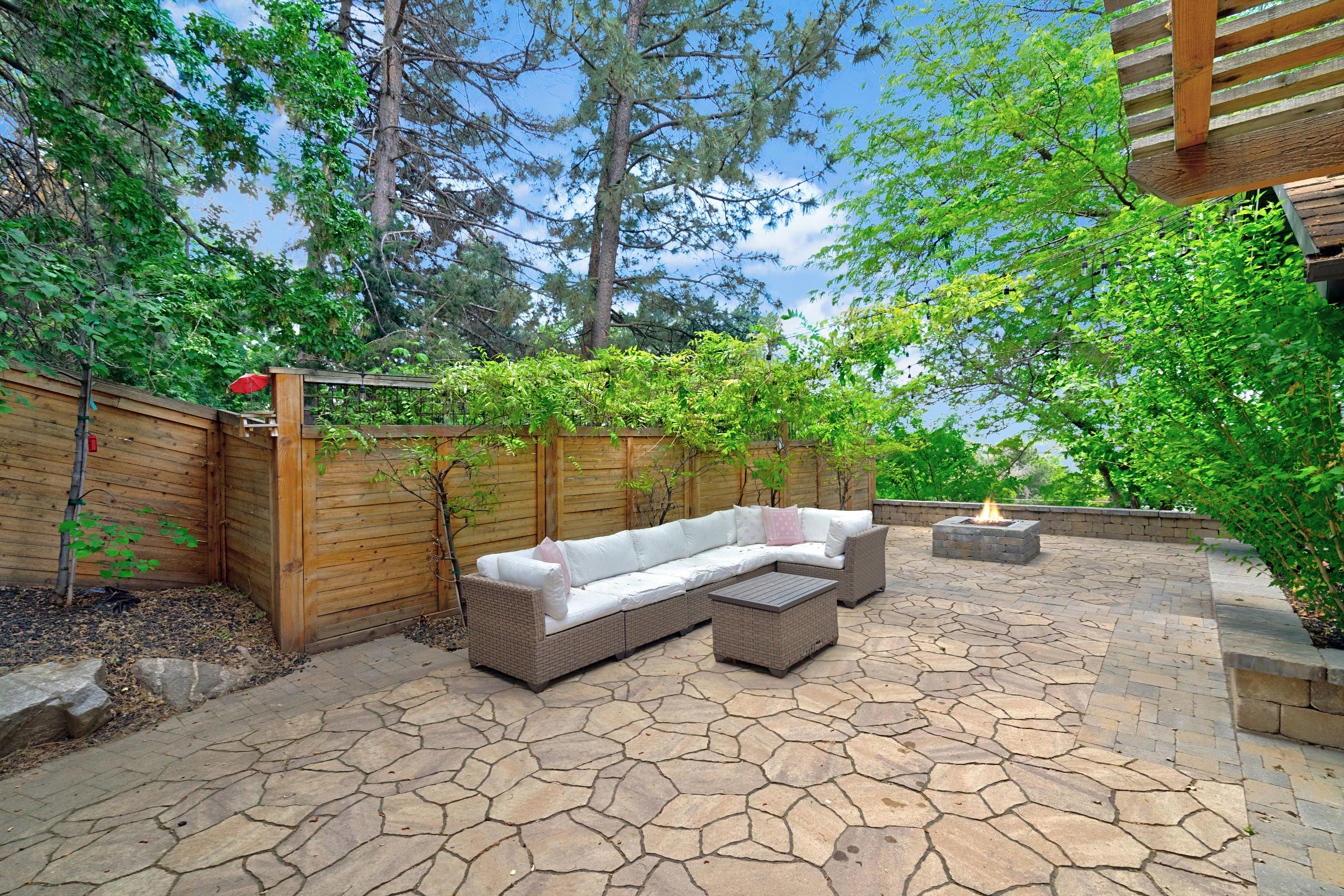 Expansive stone patio featuring a built-in fire pit and wood privacy fencing