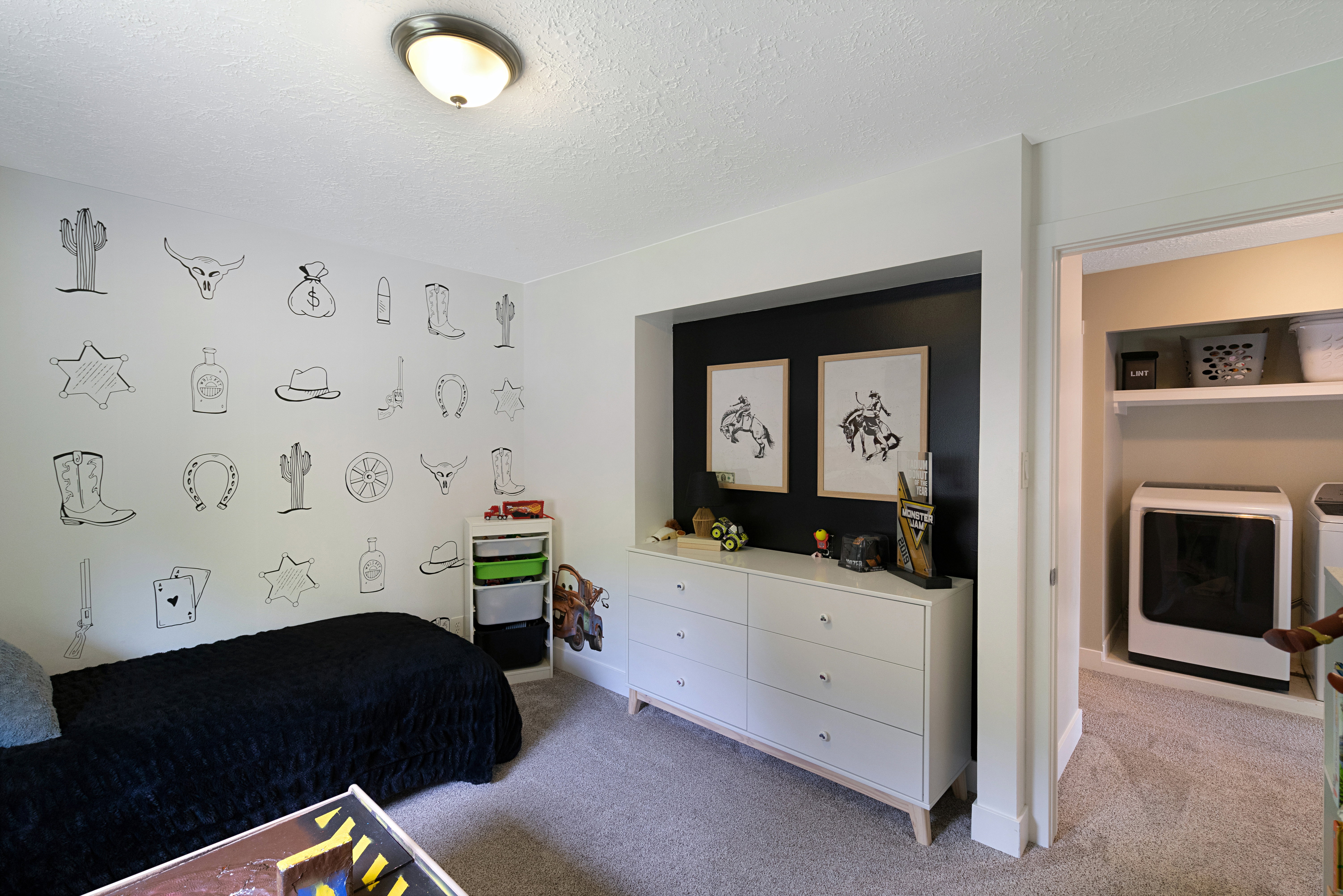 Carpeted room with a flush-mount ceiling light and a built-in laundry area featuring shelving and appliances
