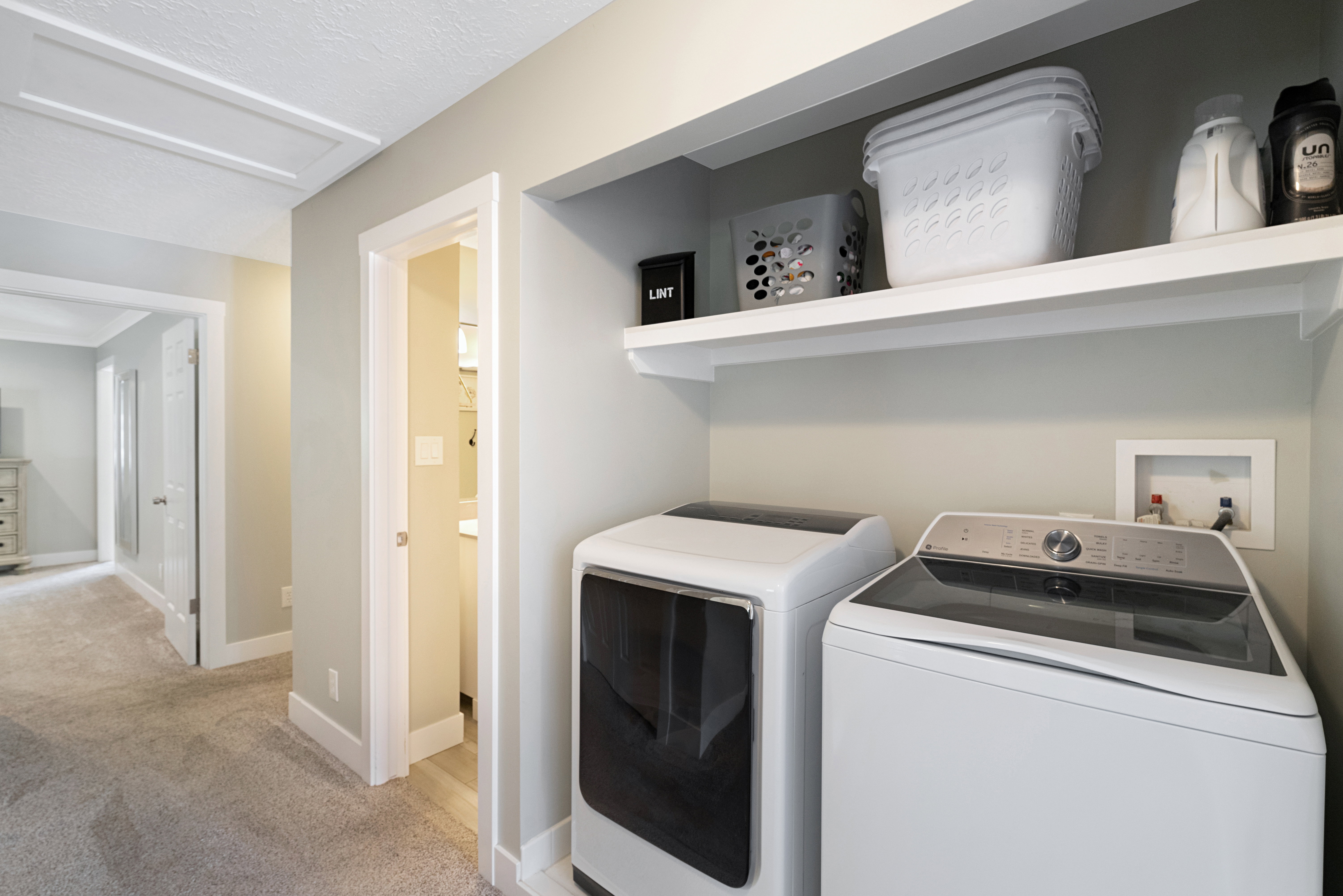 Dedicated laundry area featuring a built-in white shelf and connections for a washer and dryer