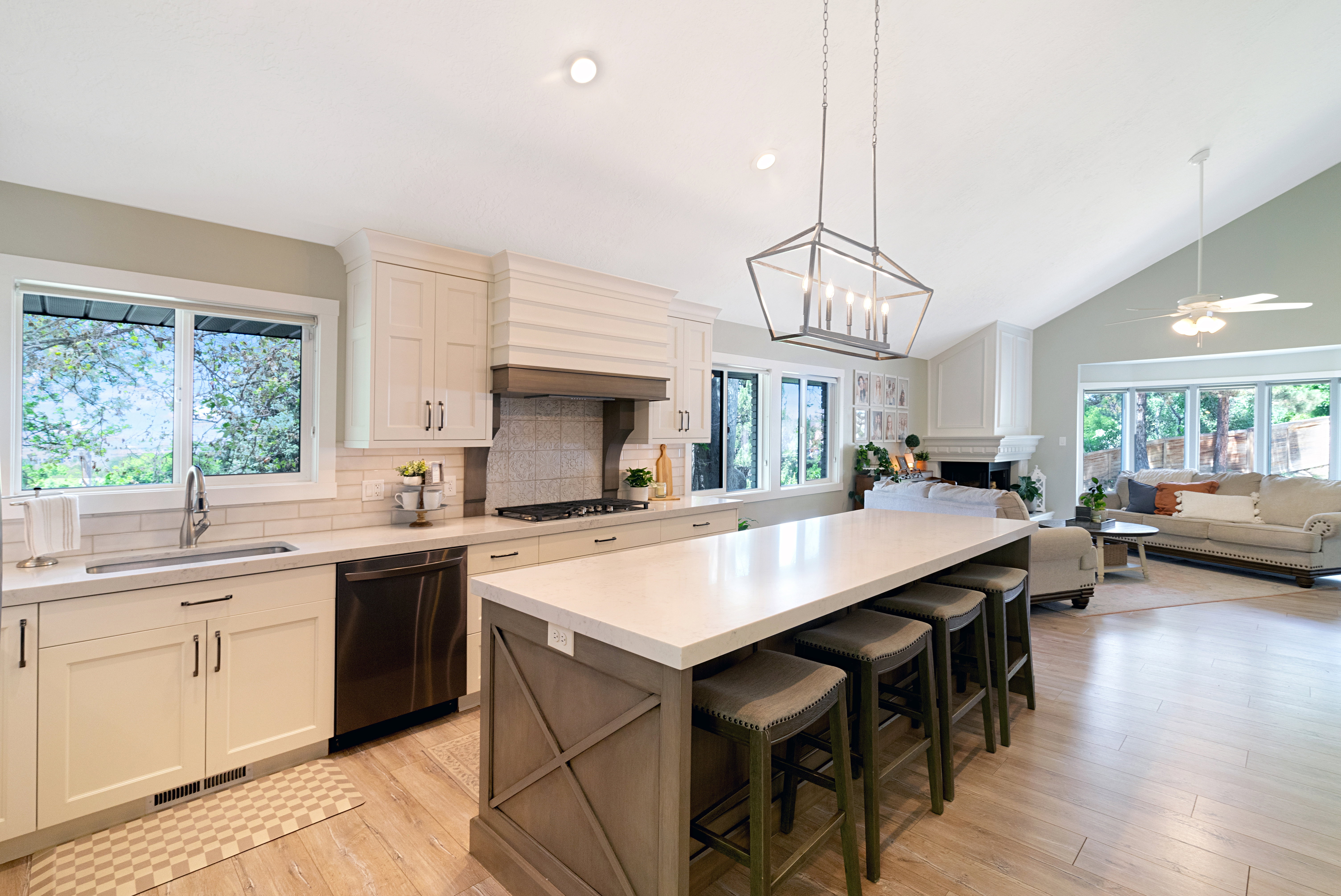 Open-concept living space featuring a kitchen with light-toned cabinetry, a large central island with seating for four, and a subway tile backsplash
