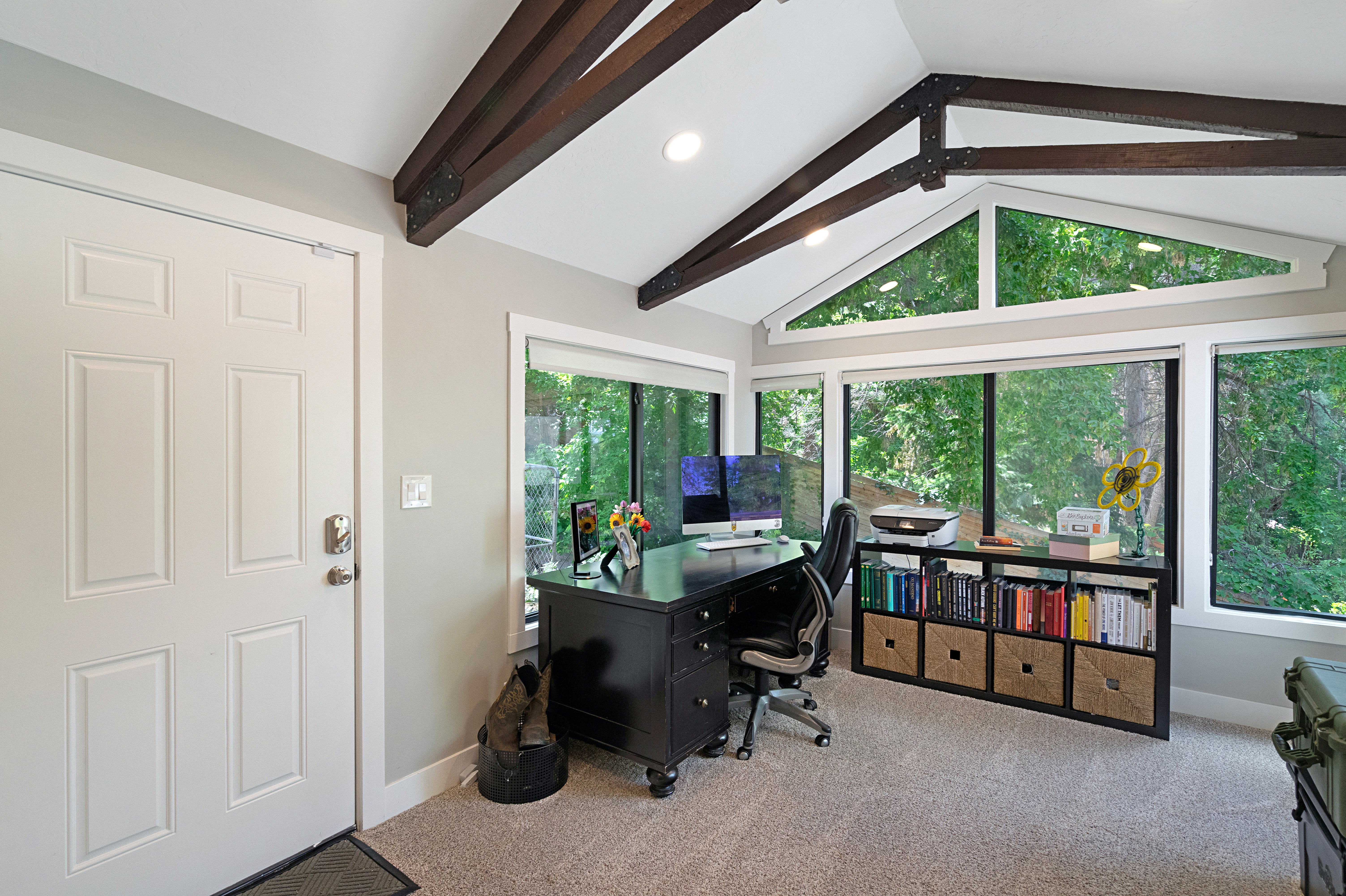 Vaulted ceiling with exposed wood beams, large picture windows, recessed lighting, carpet flooring, and a paneled entry door